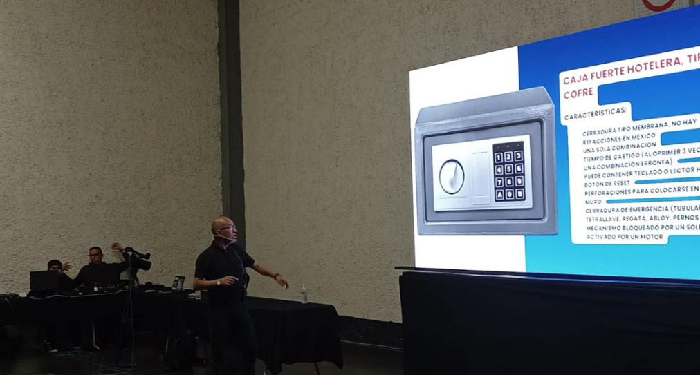 Presentador en una conferencia explicando un caja fuerte moderna con pantalla táctil a gran pantalla.