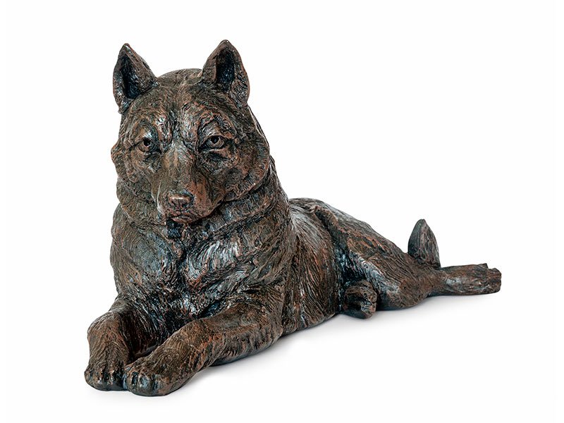 A cast resin figurine urn of a reclining Husky with detailed fur texture, calm expression, extended front legs, and relaxed tail, set against a white background.