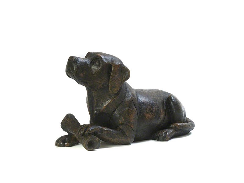 A cast resin Dog and Bone figurine urn, with a bronze finish, showcasing detailed features and a relaxed posture.