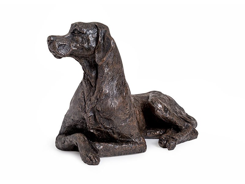 A cast resin figurine of a reclining Pointer urn with its head turned, showcasing detailed fur textures, set against a white background.