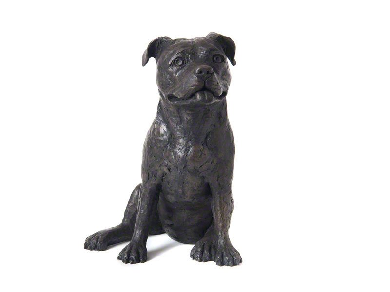 A cast resin figurine urn of a Staffordshire Bull Terrier sits against a white background, lifelike with detailed features and a friendly expression.