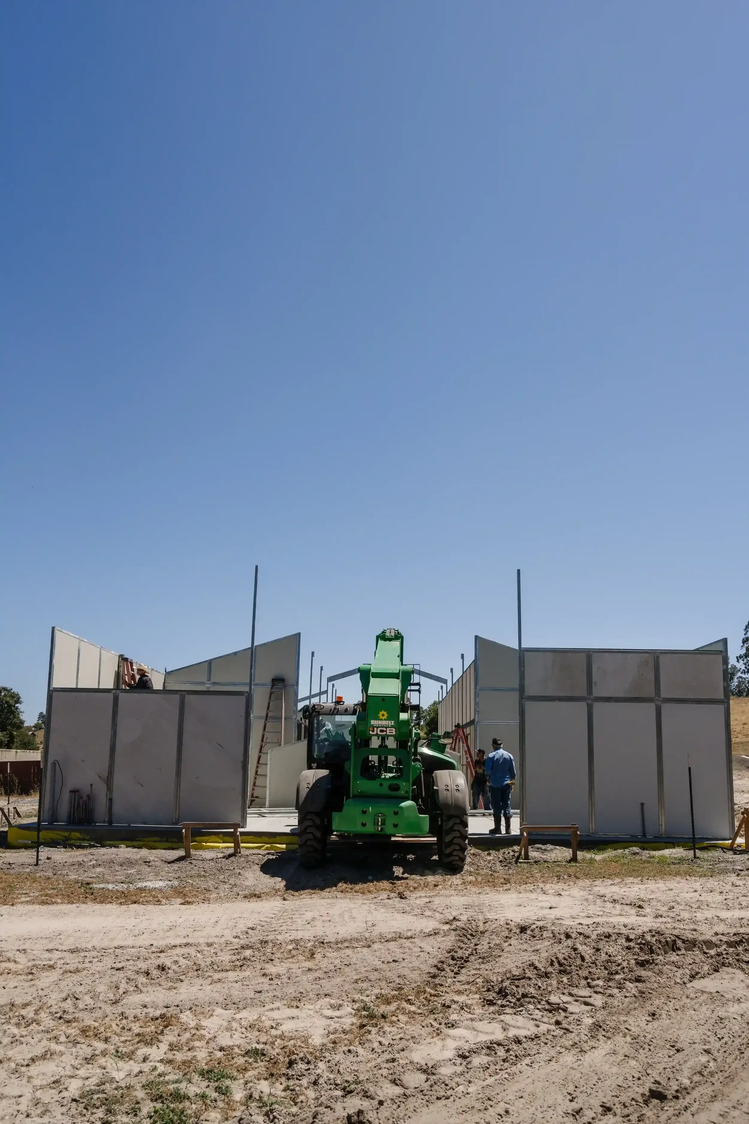 a-large-green-and-white-truck-is-parked-on-a-dirt-field.webp
