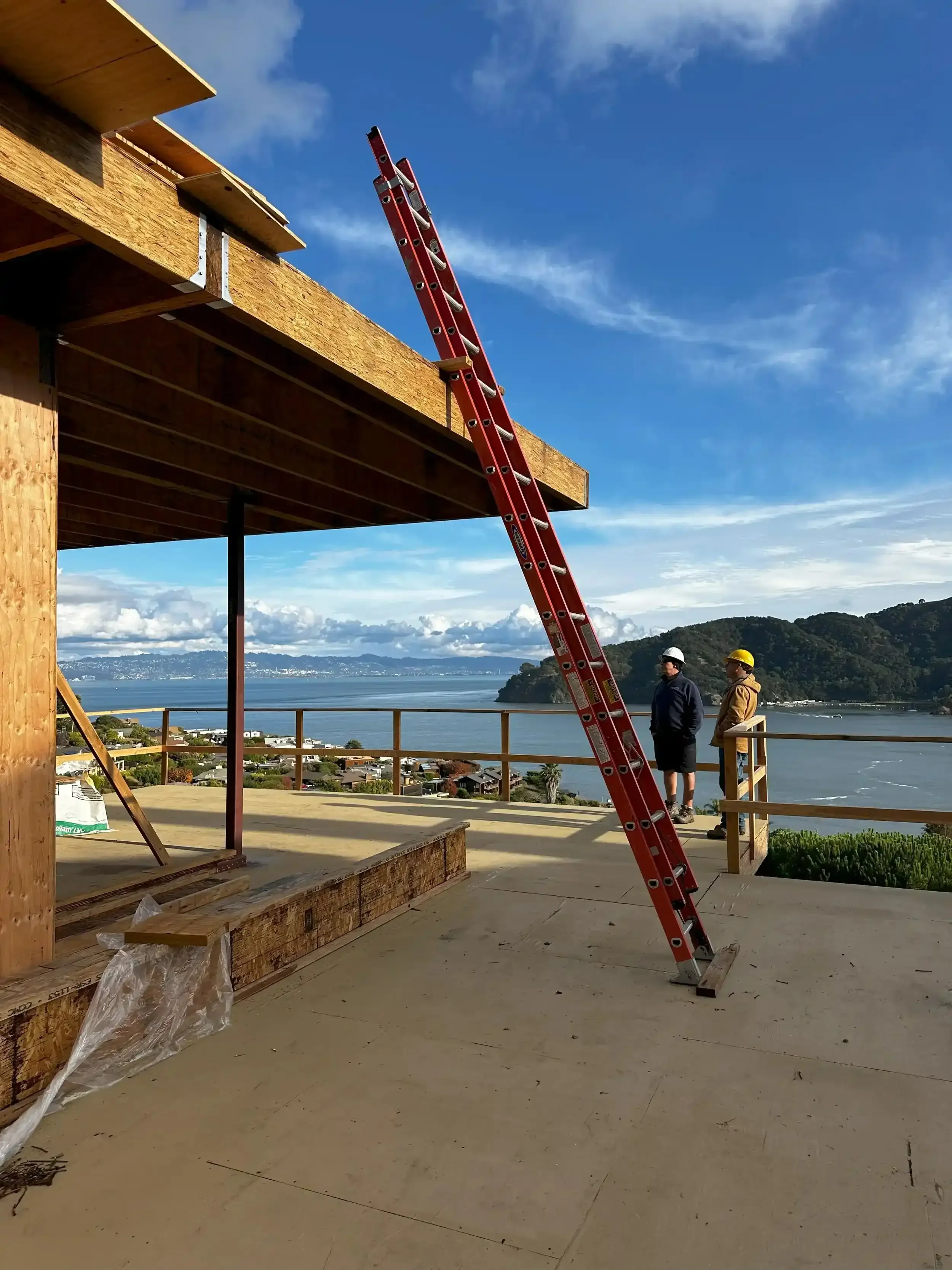 a-crane-is-attached-to-a-wooden-pole-near-a-building.webp