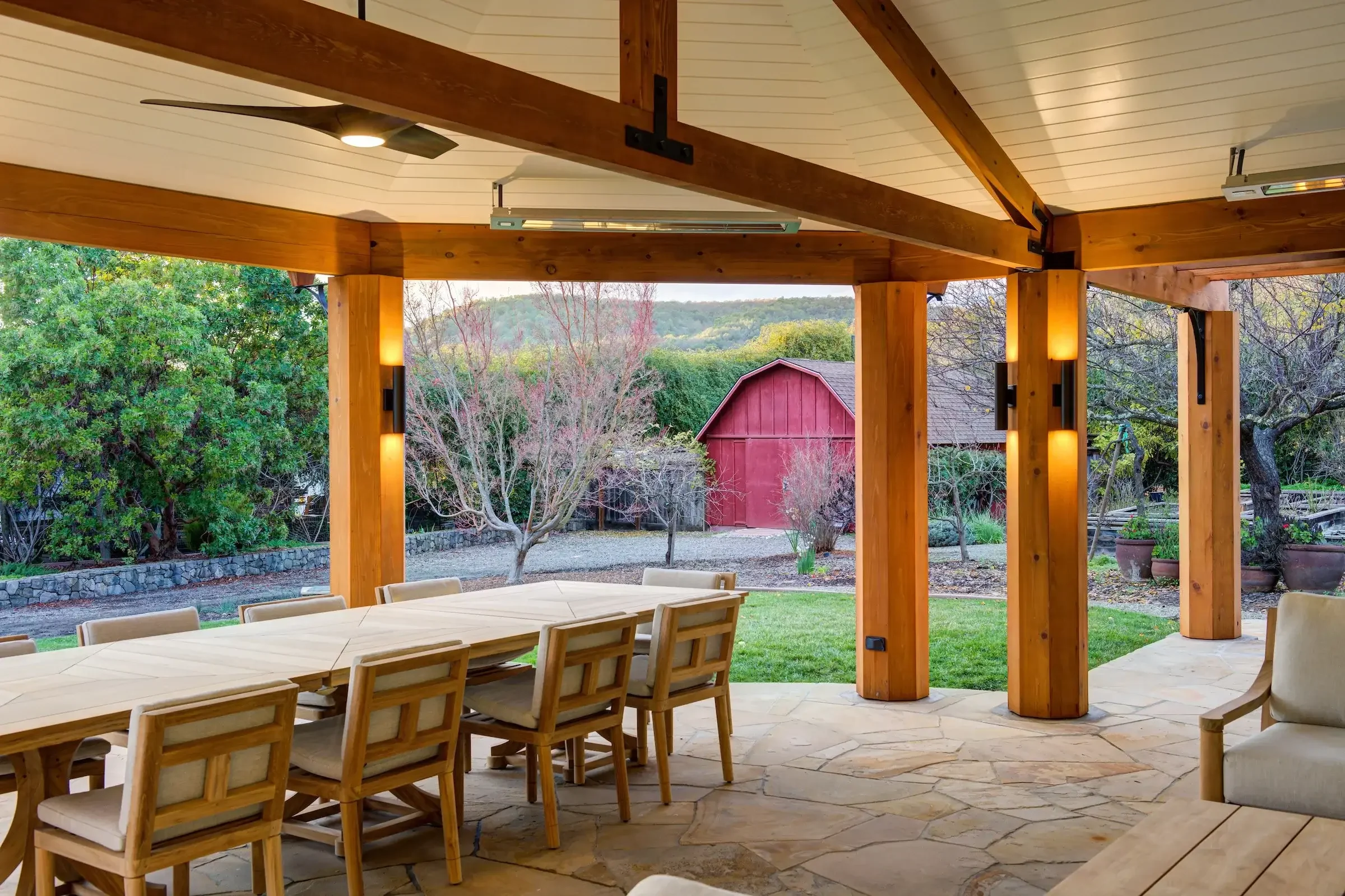 A wooden table with a wooden bench and a barn at the back 