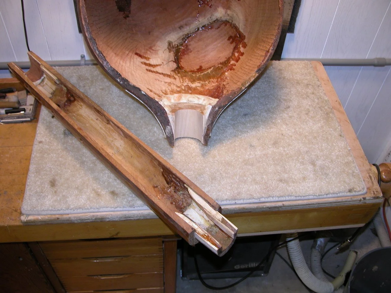 Wooden bowl in progress on a workbench, showing the interior being hollowed, with wood shavings around.