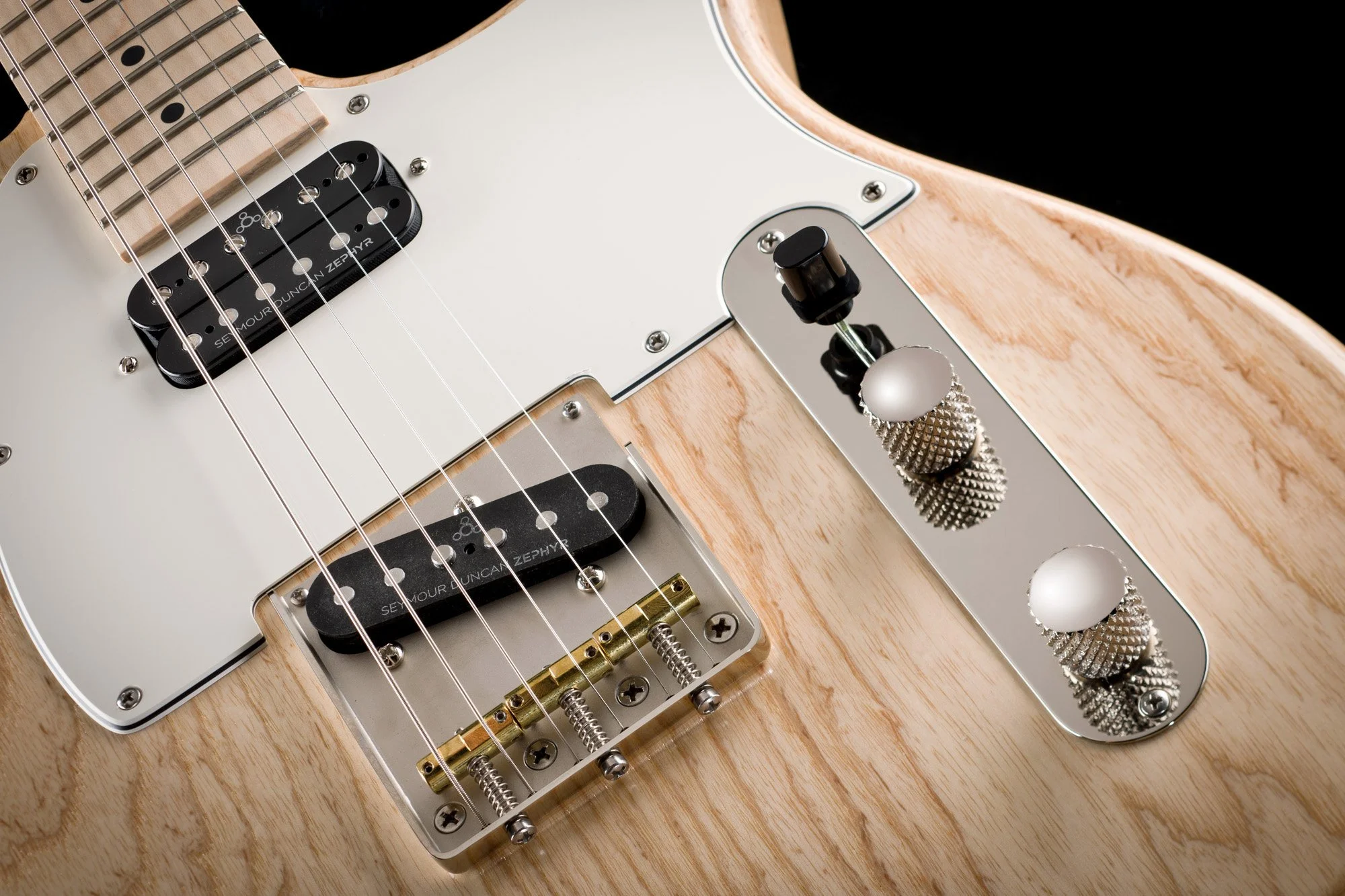 Close-up of an electric guitar showing pickups, strings, and control knobs on a wooden body.
