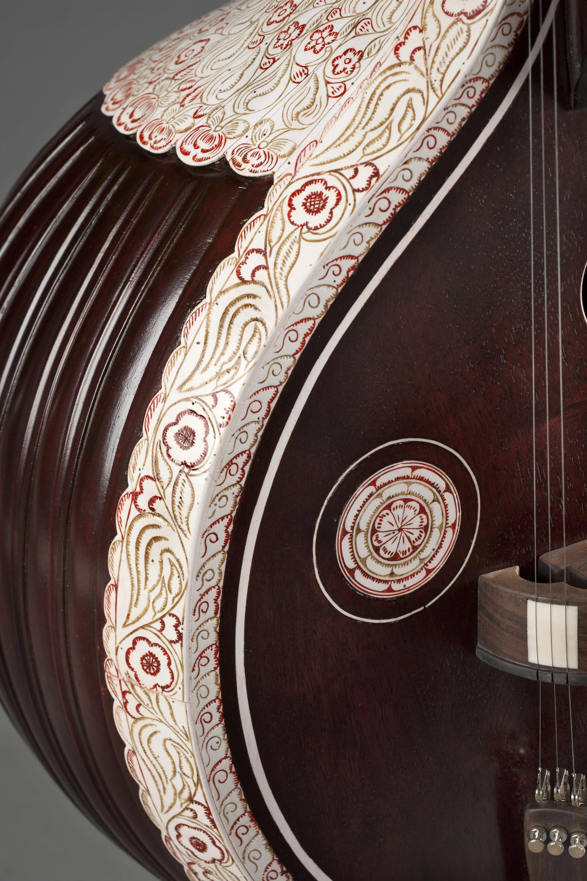 Close-up of a decorated sitar with intricate floral patterns and carvings on its body.