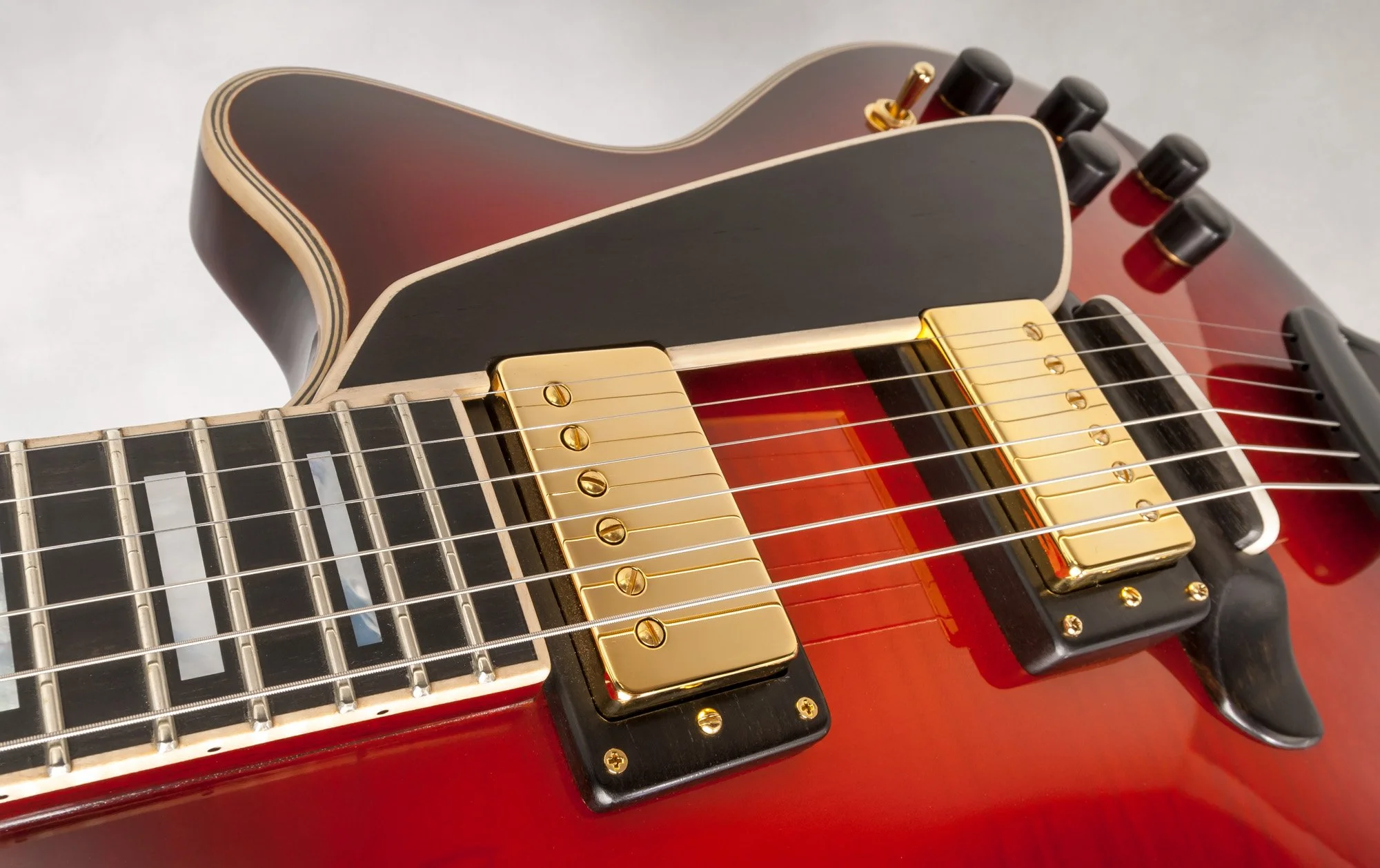 Close-up of electric guitar with golden pickups and red body.