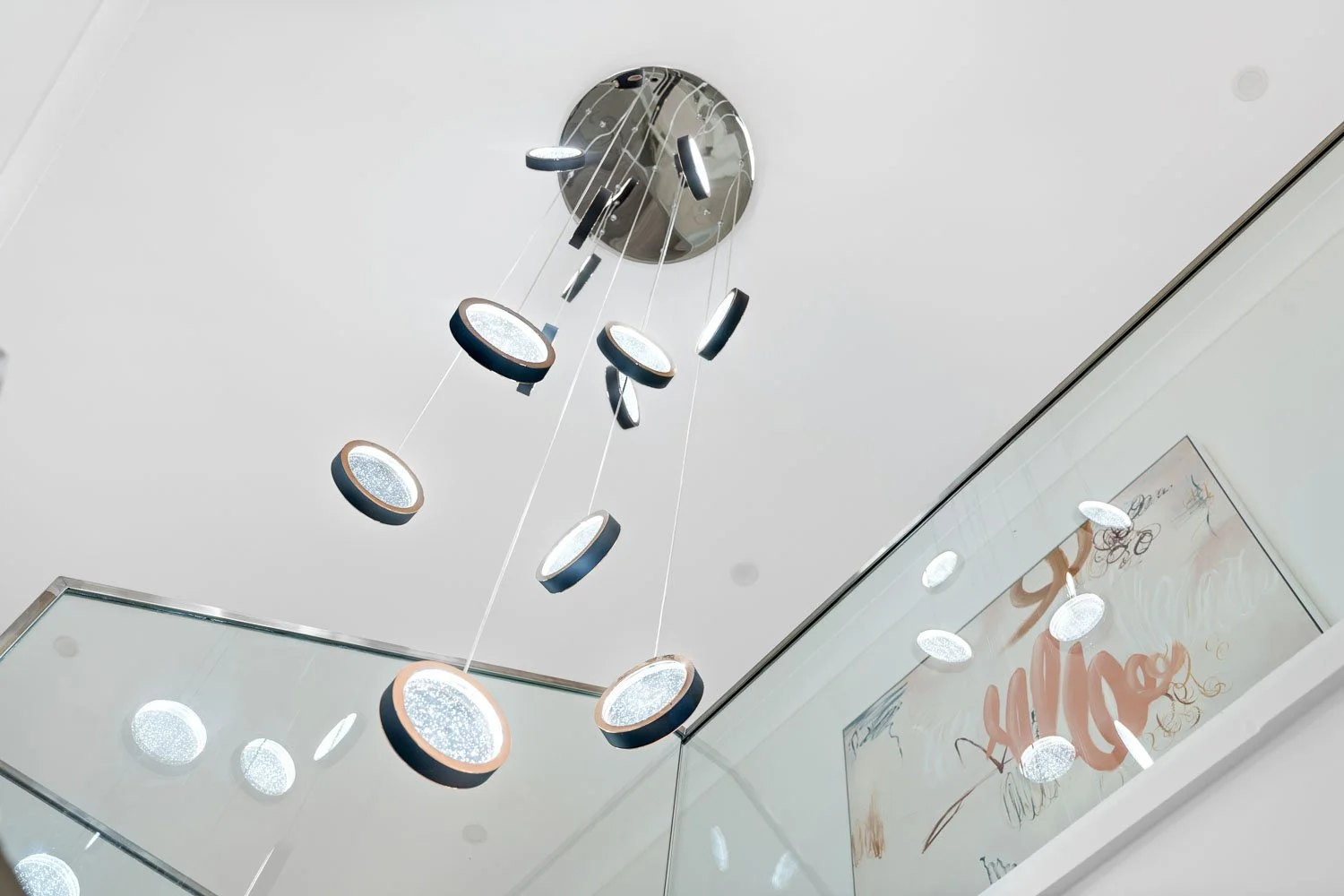 Modern ceiling chandelier with multiple circular LED lights hanging from a white ceiling.