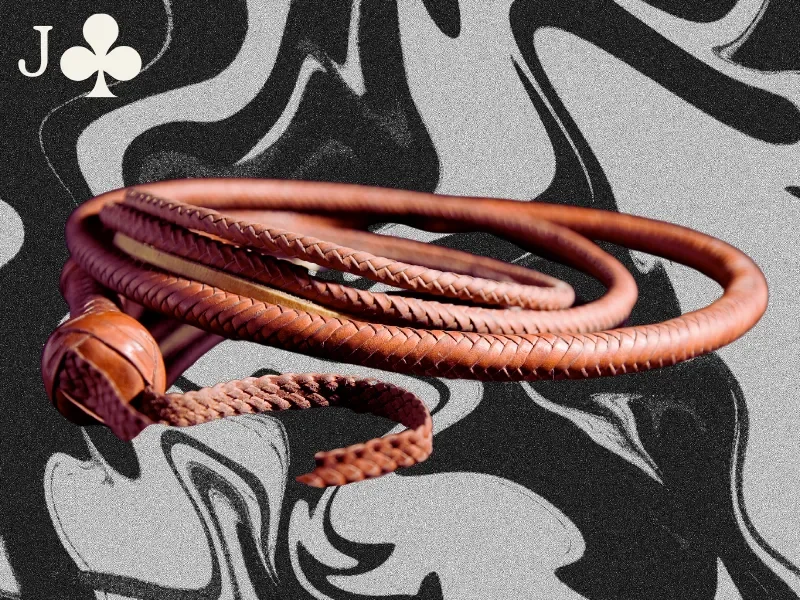 A red braided whip is pictured on a marbled black and gray background. A white jack of clubs card symbol is in the upper left hand corner of the image.