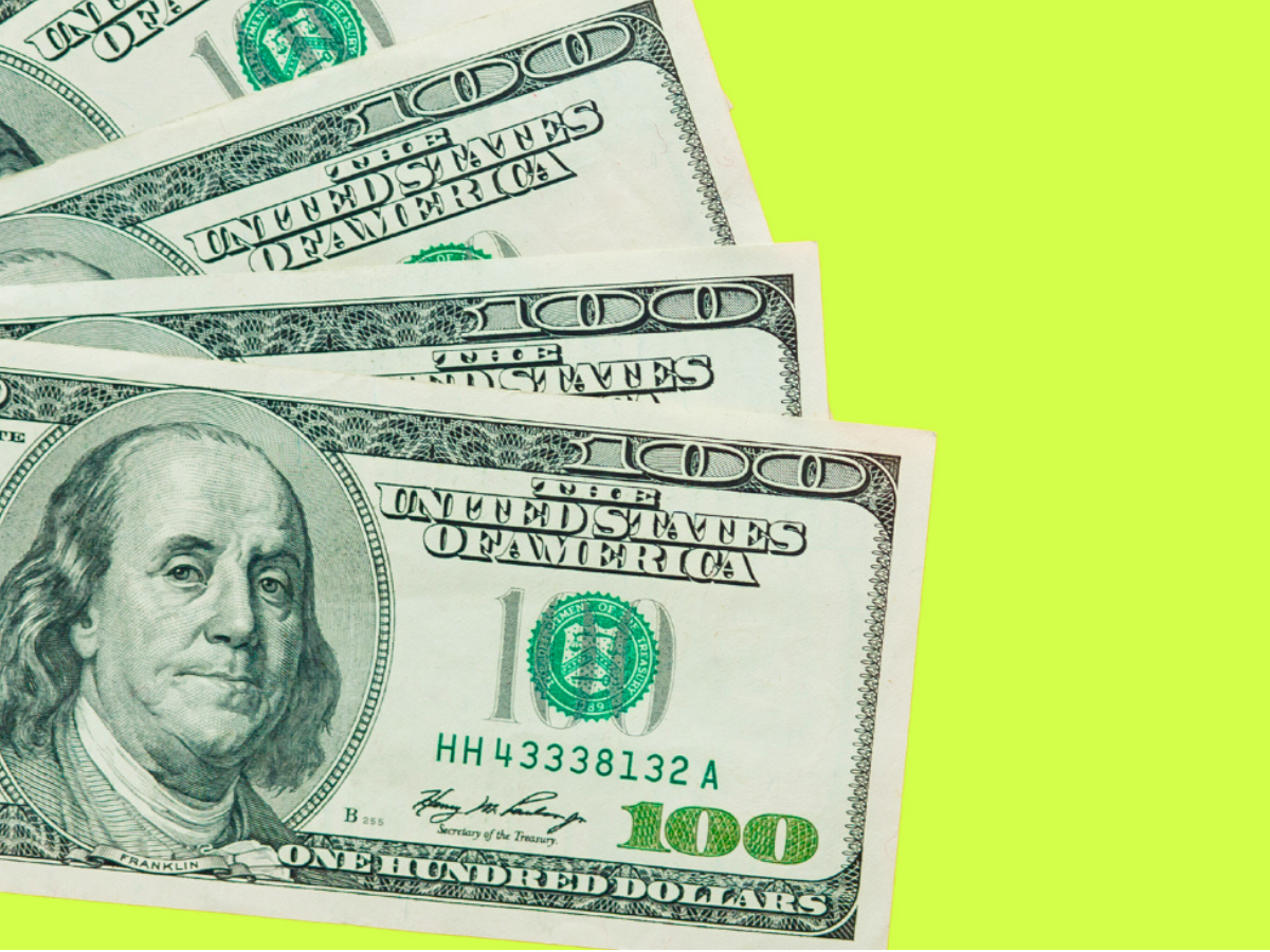 A stack of hundred-dollar bills against a lime green background.