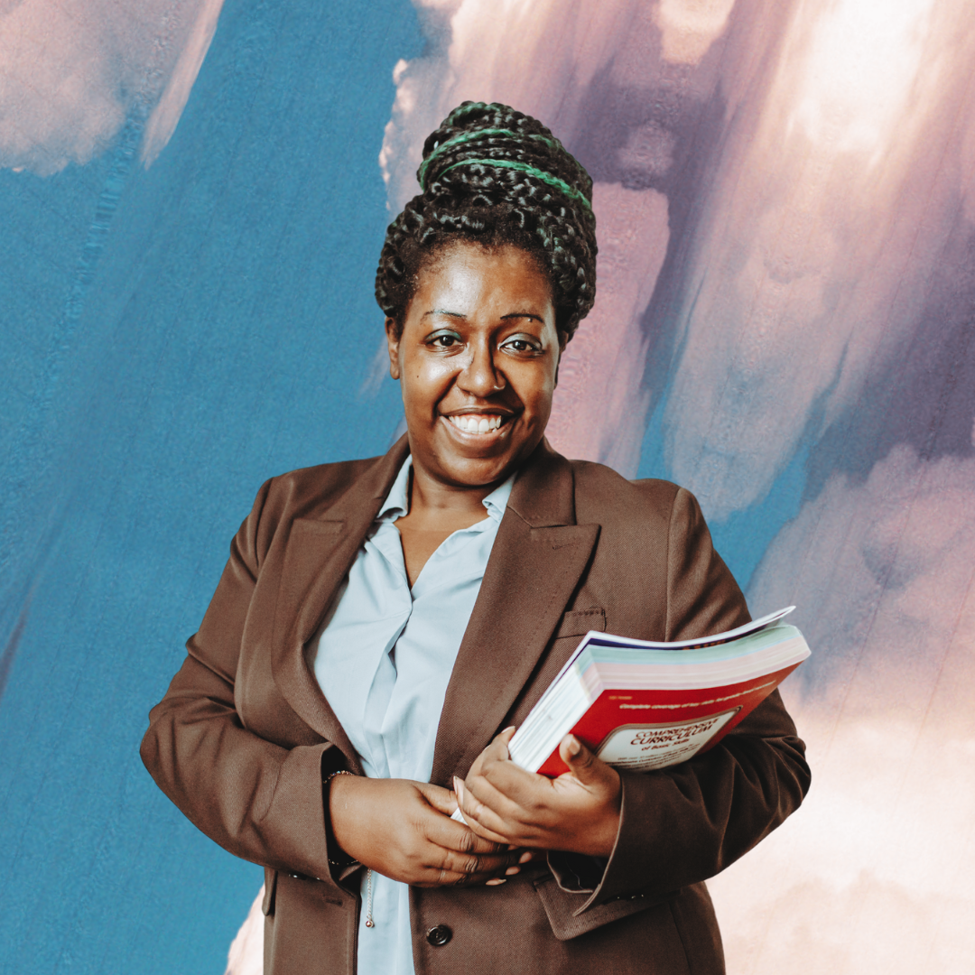 A Black person in a brown suit jacket and white button down smiles at the camera while holding a stack of books. They are pictured in front of a blue, pink, and white marbled background.