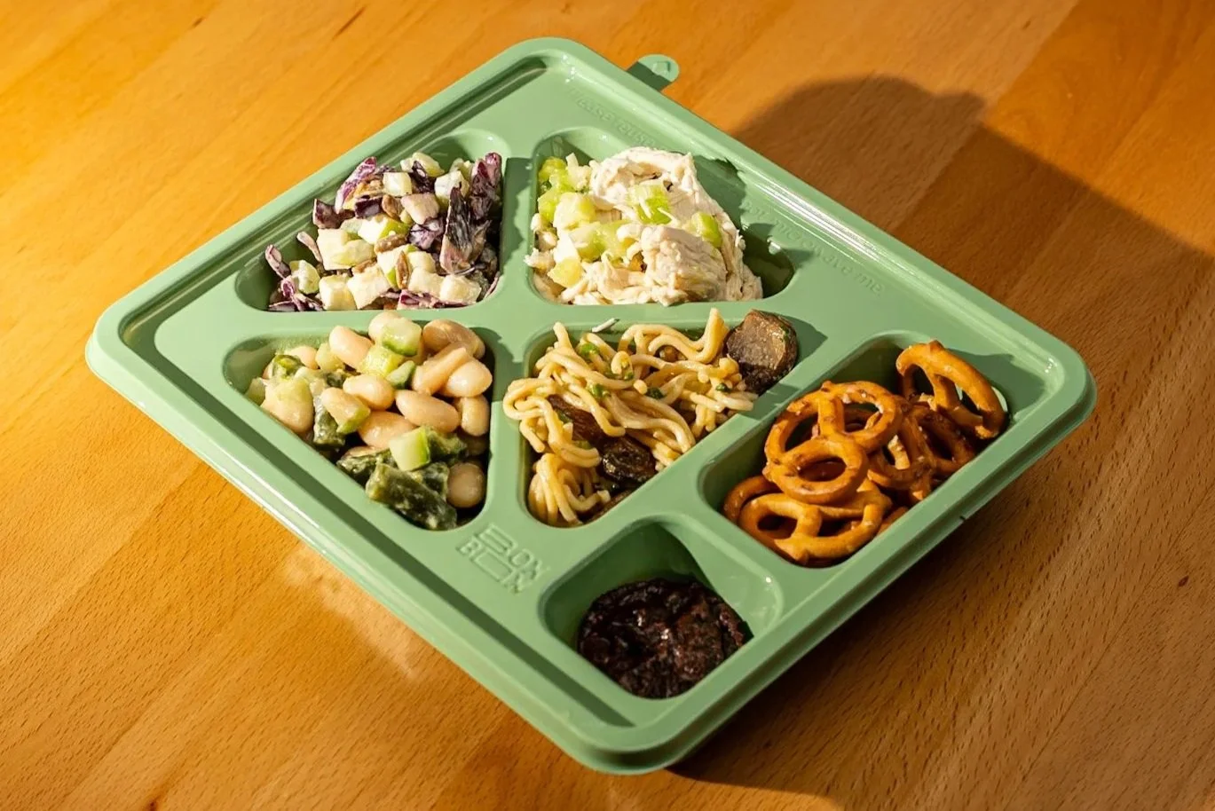 Gluten-free bento box with chicken salad, noodles, veggies, and more