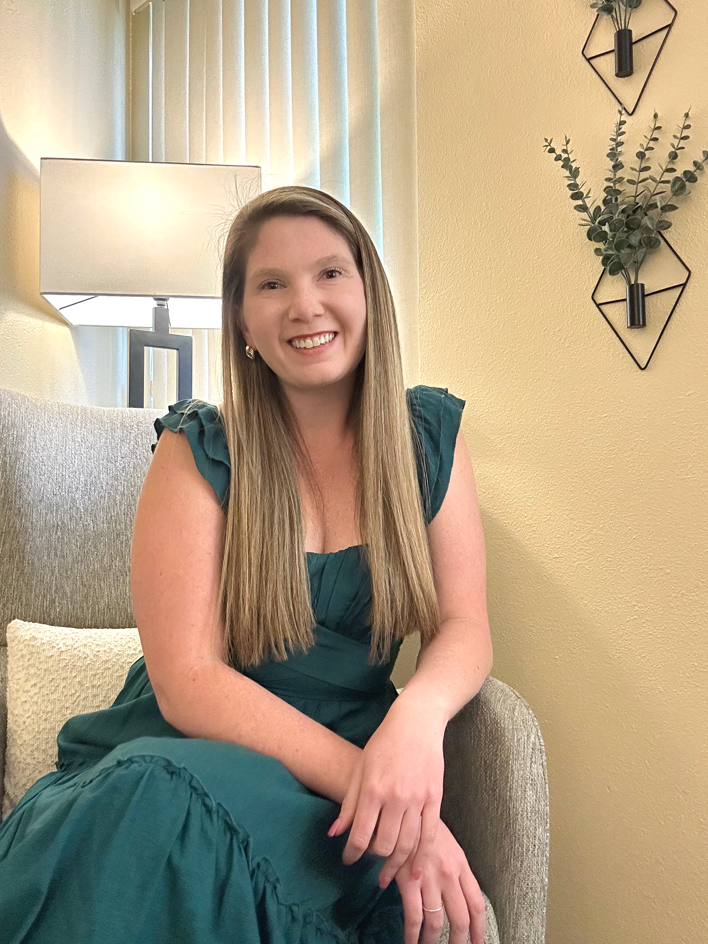 female therapist in Denver, anxiety therapist in Denver, relationship trauma therapist in Denver, therapist smiling at camera, warm lighting and comfort from therapy space