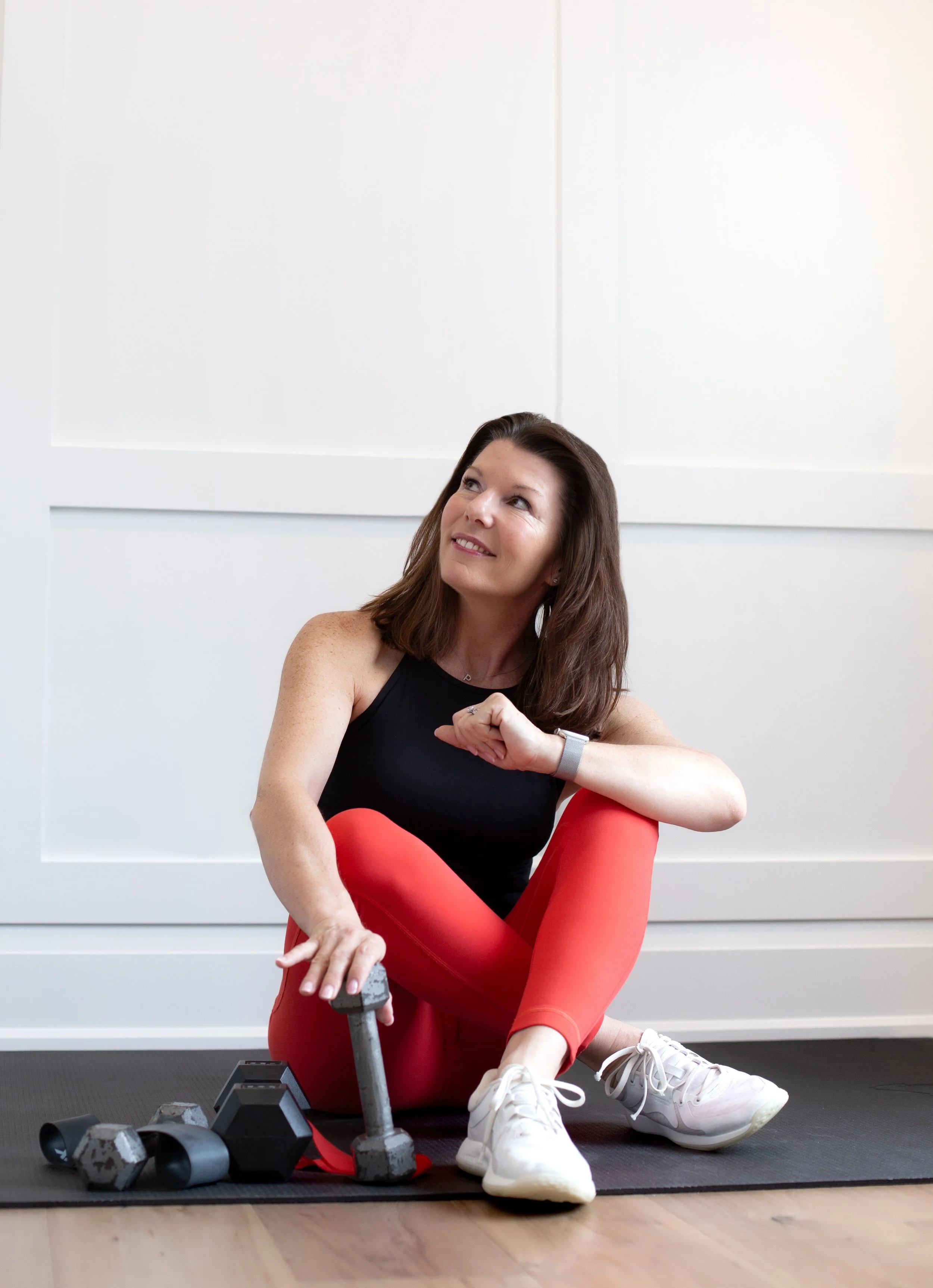 Woman with long hair wearing a knitted top, posing seated indoors.