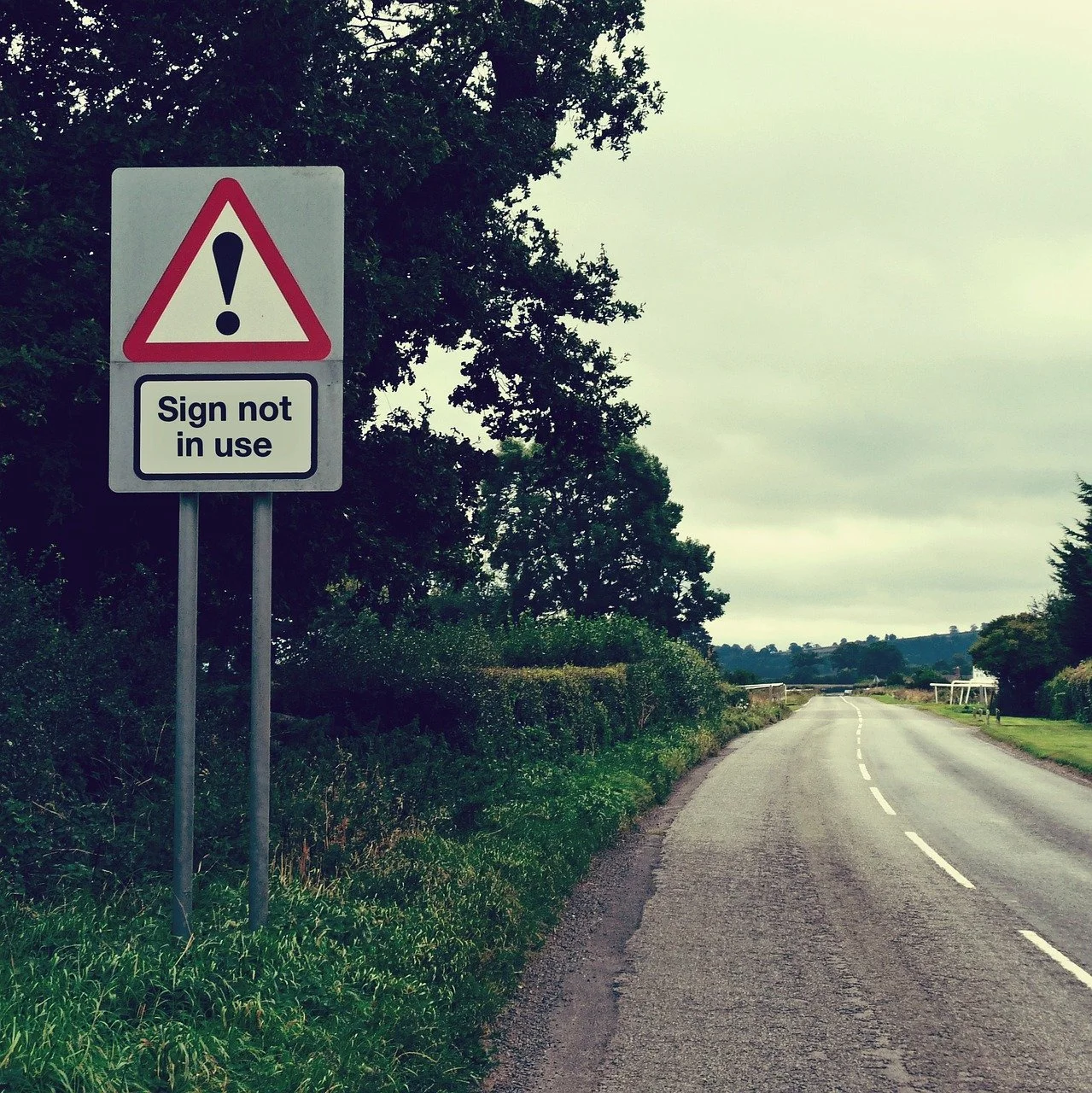 Sign on a deserted road says 'sign not in use'