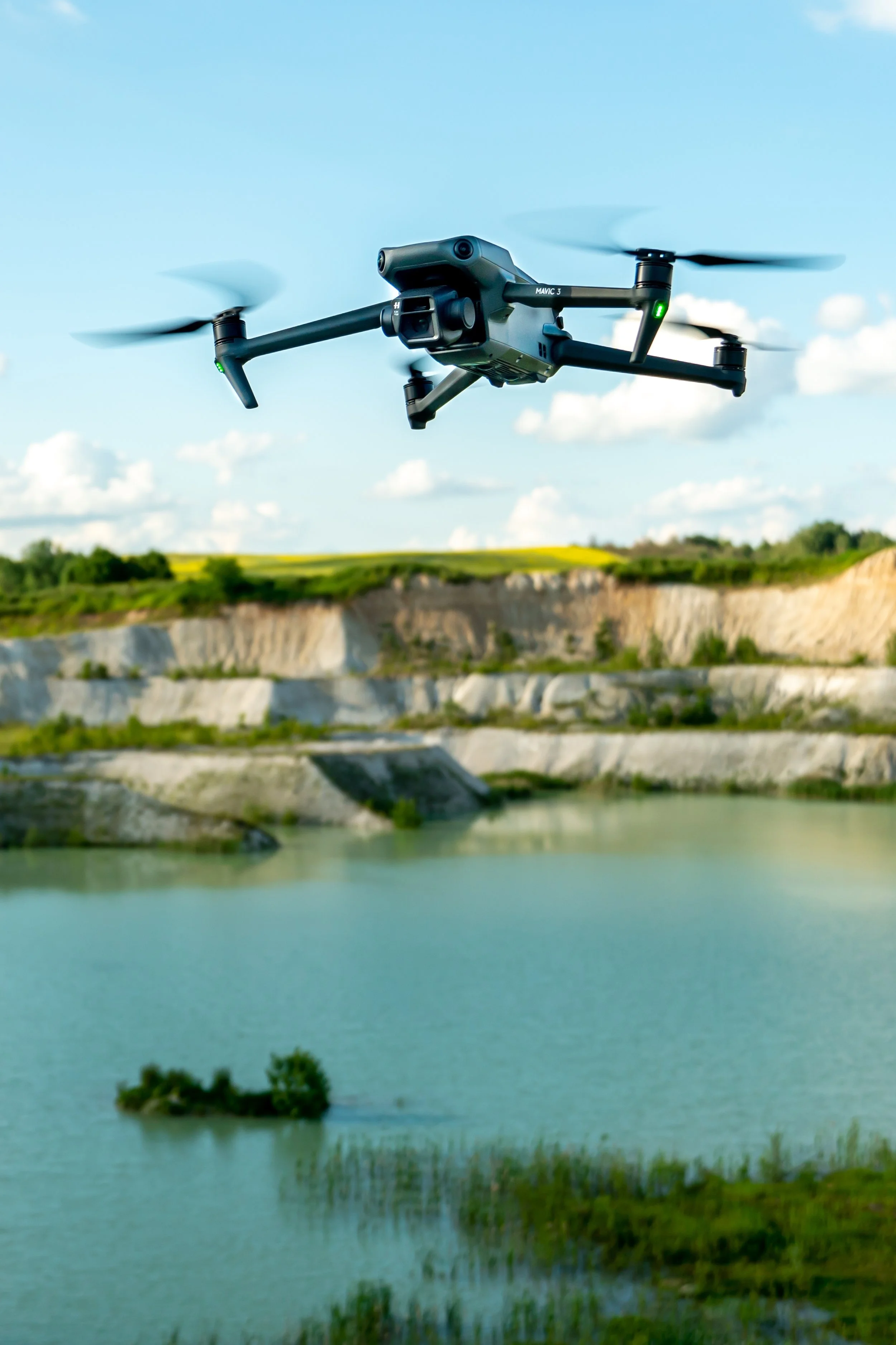 A drone flying over a river with a landscape of cliffs and greenery in the background.