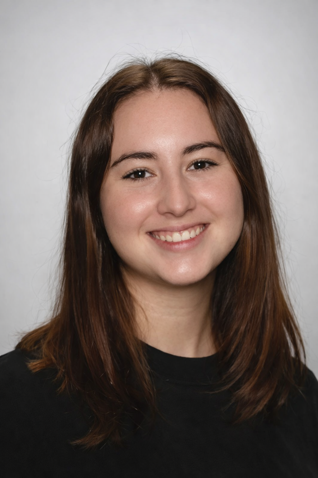 A young woman with brown hair smiling at the camera, wearing a black top.