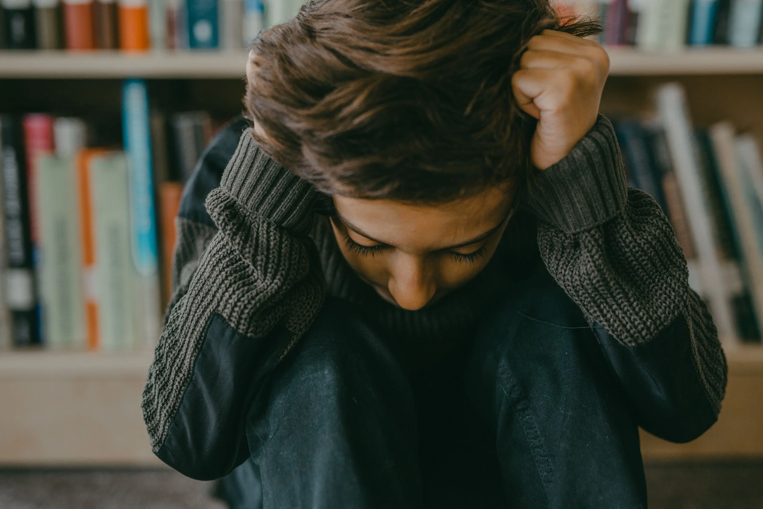 An anxious child holding their head at a desk, representing school stress and family counseling services in Bergen County NJ.