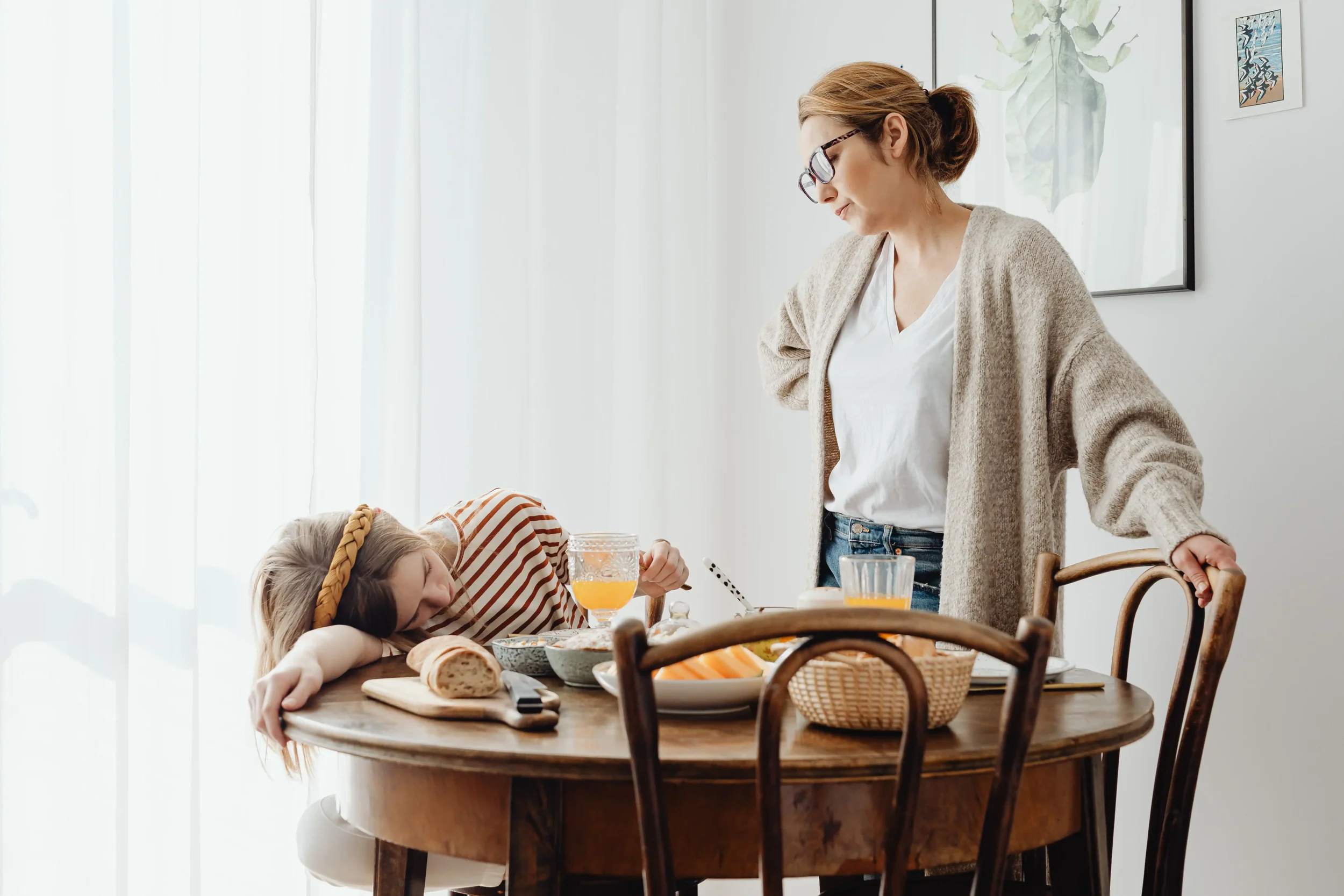 A tired mother and exhausted child at the breakfast table, capturing the daily stress and parental burnout experienced by busy families.