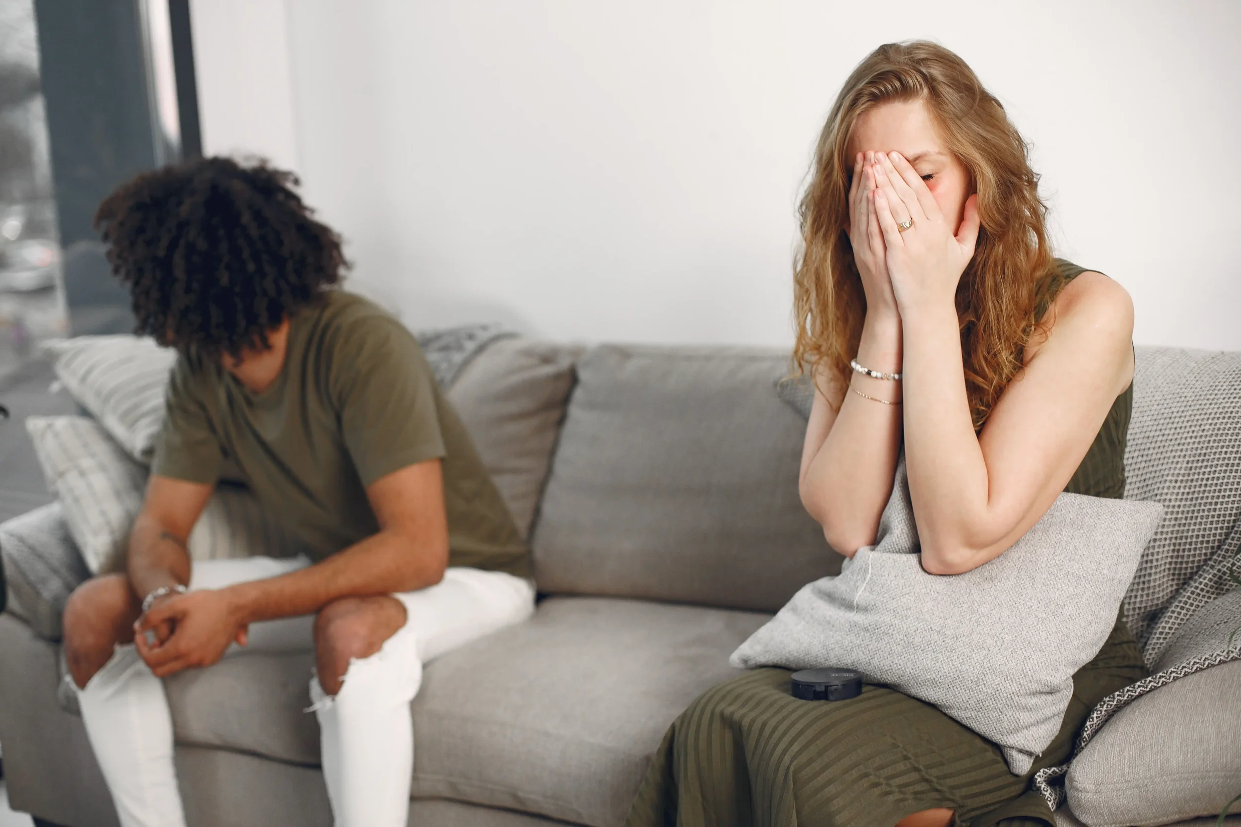 A distressed couple sitting apart on a couch, capturing the emotional disconnection and quiet relationship struggles hidden behind a successful exterior.