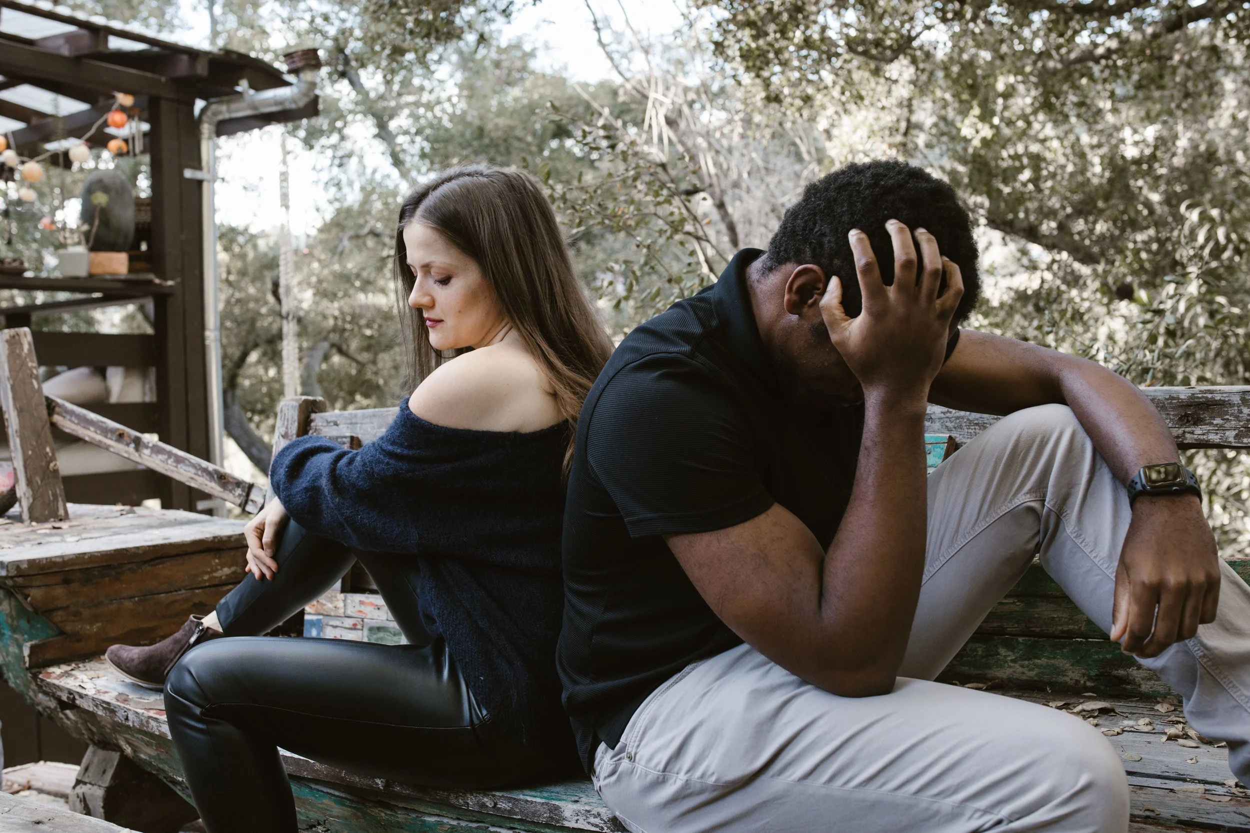 A couple sitting on opposite ends looking distant and disconnected .