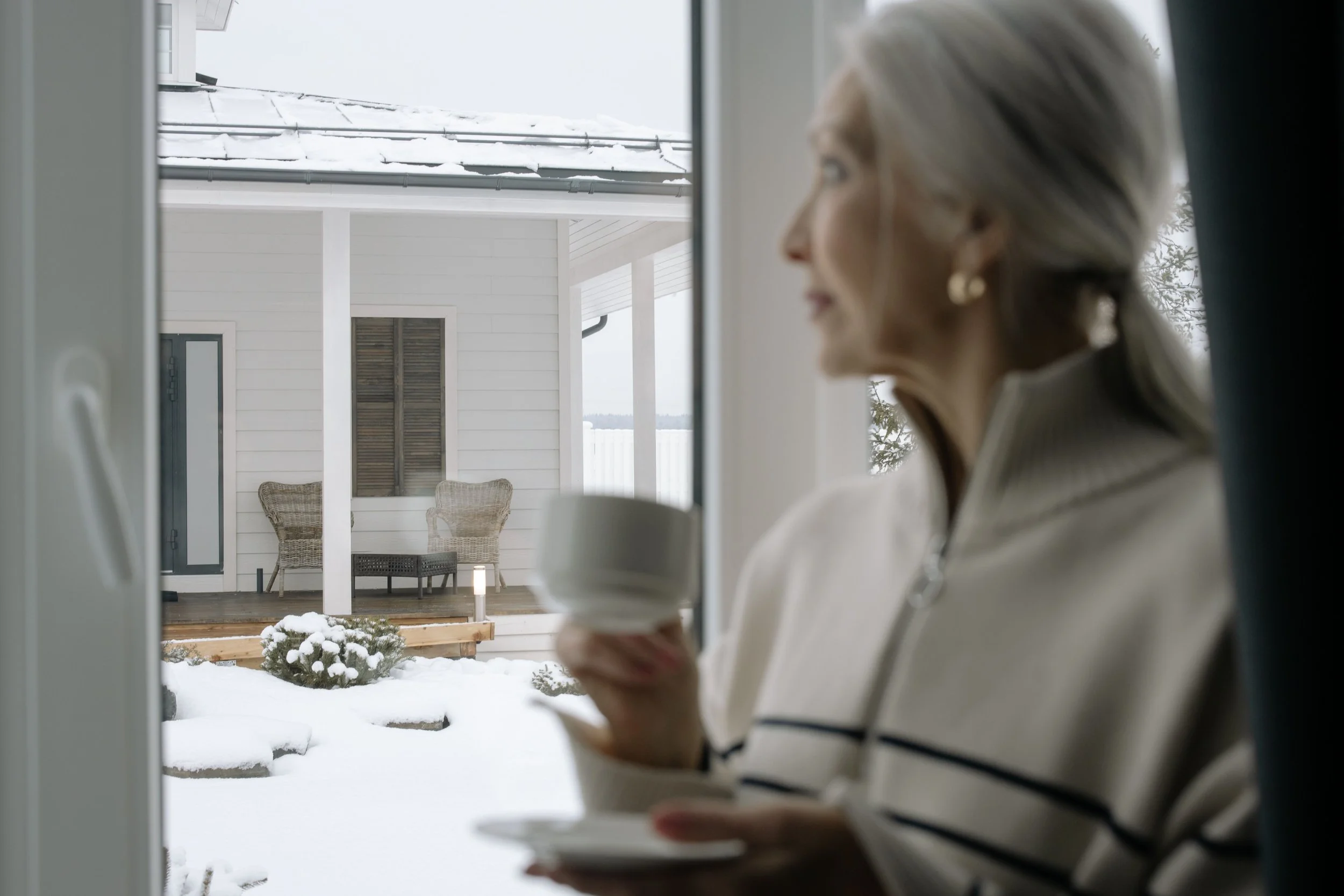 A mature woman sitting calmly , holding a warm mug and reflecting peacefully.