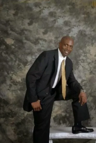 Man in suit posing with one knee up against a textured backdrop