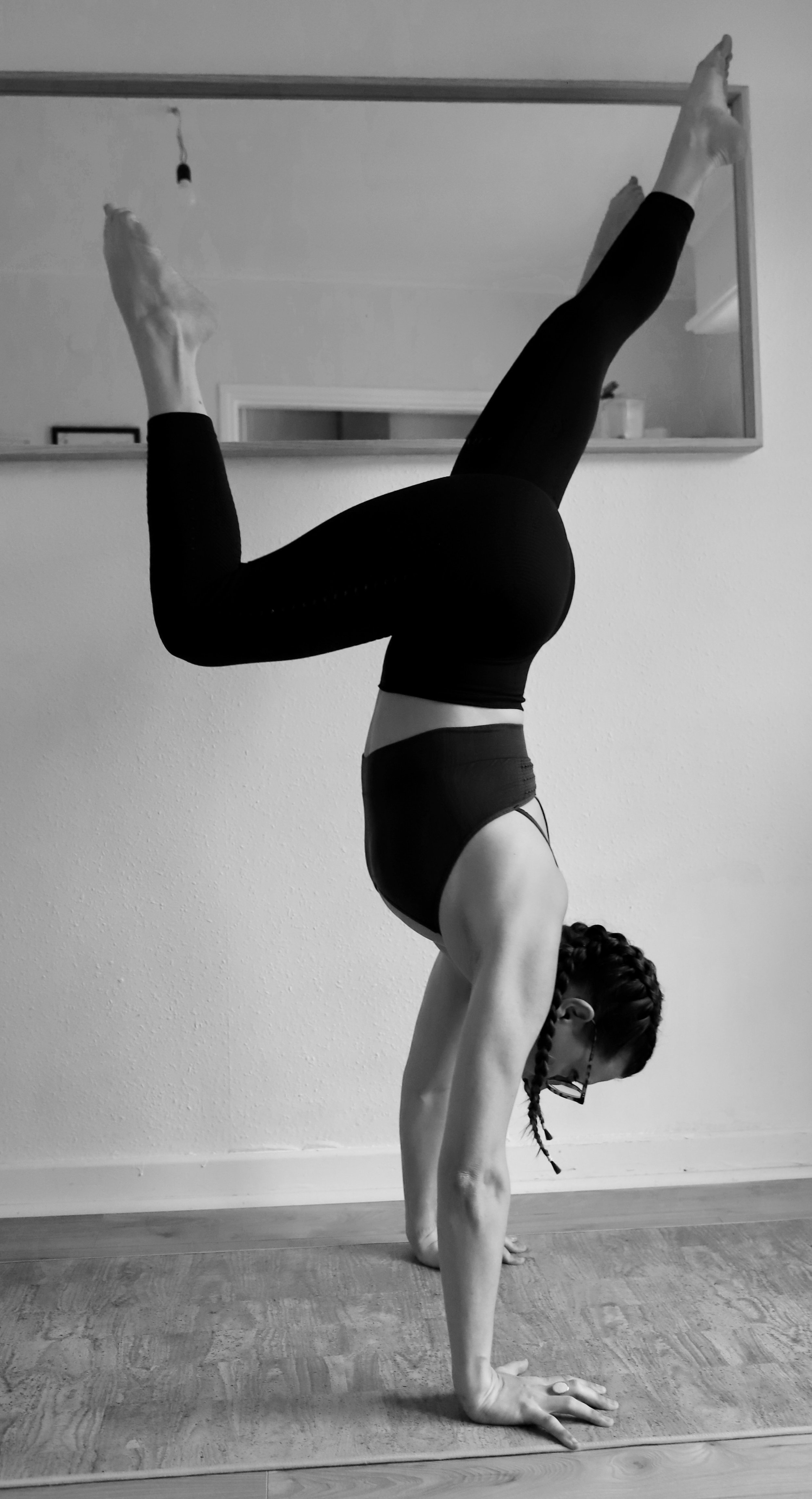 Frau führt Handstand auf Yoga-Matte im Raum aus.