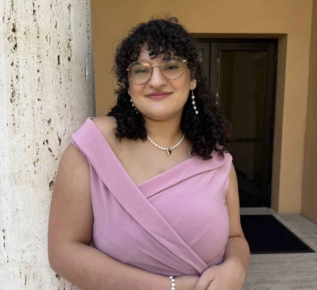 Woman in pink dress and glasses smiling