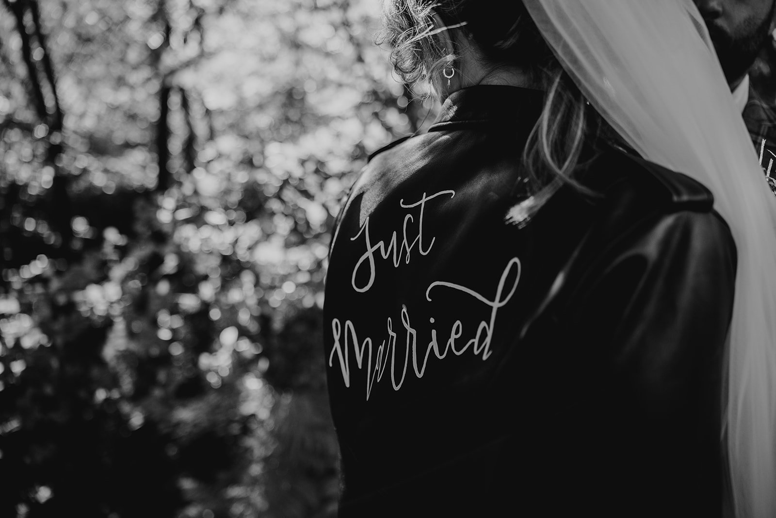 Black and white photo of a bride and groom, with the bride wearing a jacket that says 'Just Married', separate from the groom. styal lodge weddings 