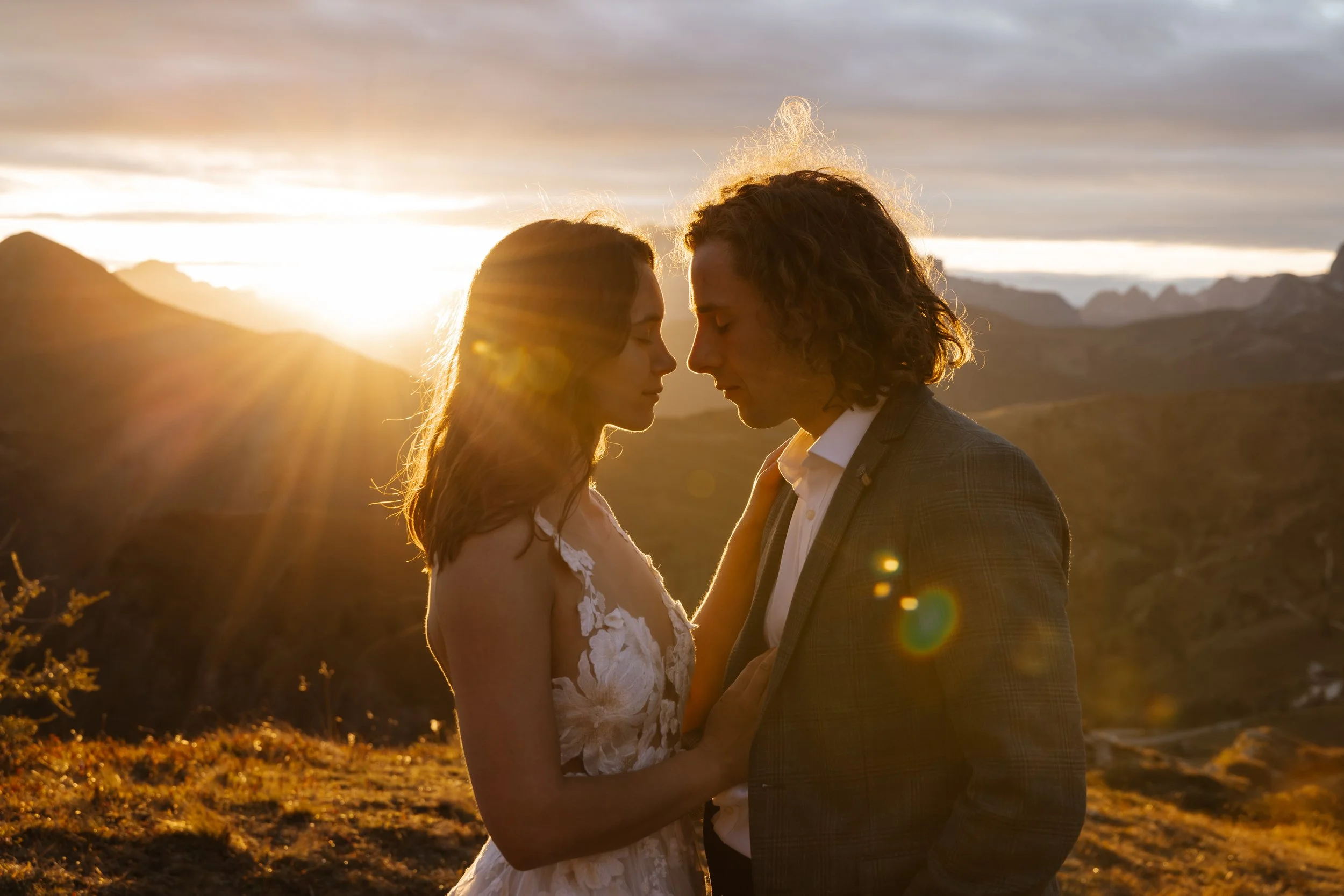 A couple standing close with foreheads touching at sunset in a mountainous landscape. documentary wedding photographer in italy