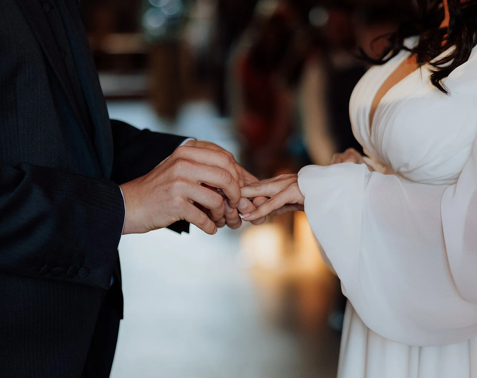 A person in a black suit places a ring on a woman's finger during a wedding ceremony. cheshire wedding venue peckforton castle 