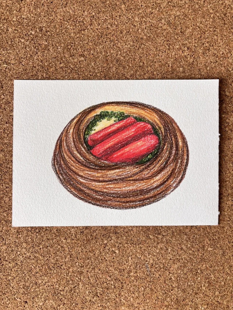 A drawing of a bowl of ramen with red noodles, green vegetables, and a brown broth, on a white sheet of paper on a corkboard background.