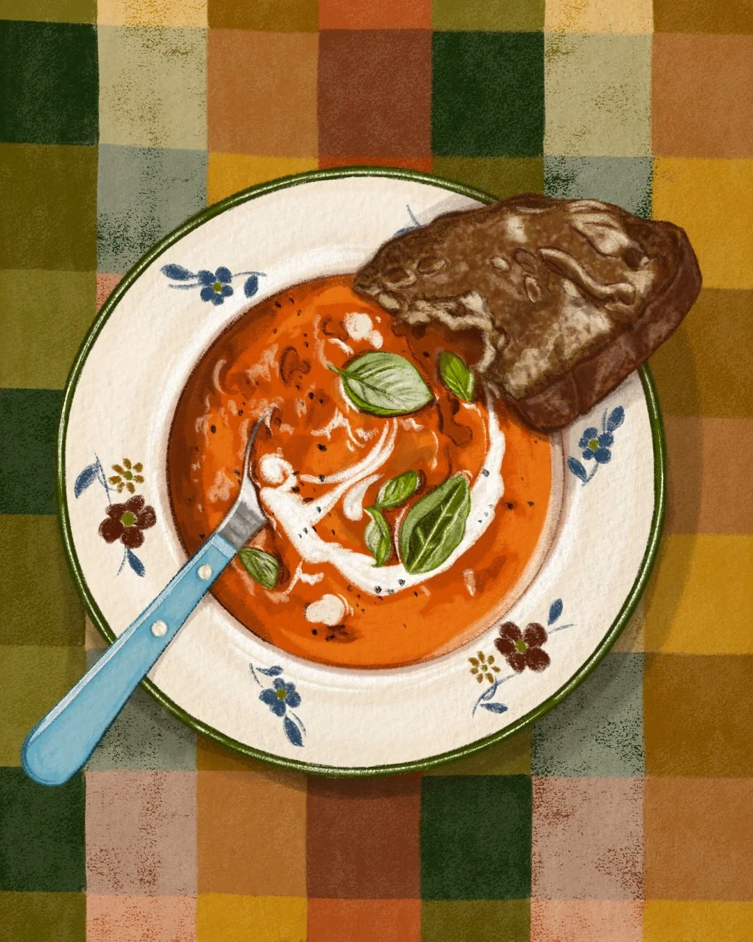 Bowl of tomato soup garnished with fresh basil leaves, with a slice of dark bread on the side, on a colorful checkered tablecloth.