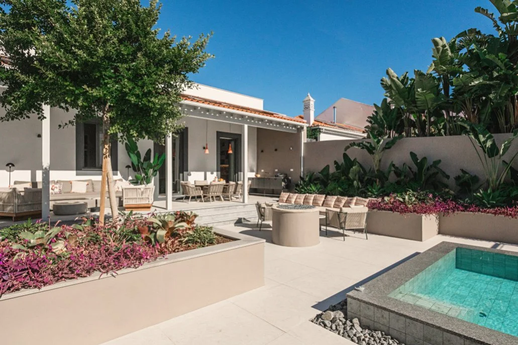 Contemporary backyard with a swimming pool, outdoor seating, and lush green plants under a clear blue sky.  Holiday rental home in Lagoa.