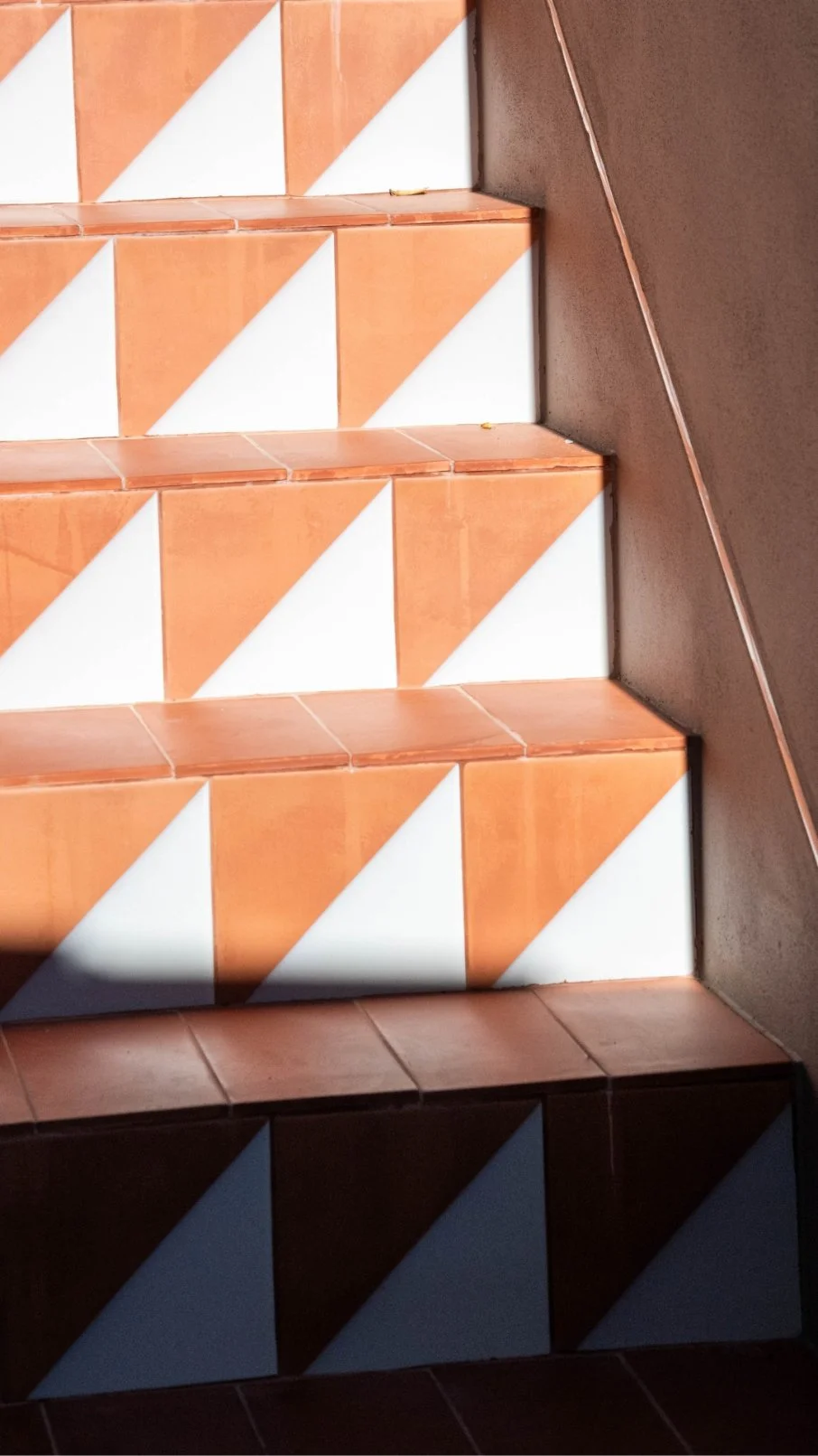 Close-up of public stairs with orange and white ceramic tiles and a brown wall on the right side.  Holiday rental home in Lagoa.