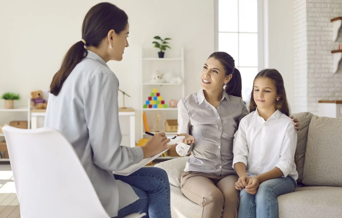 Therapeutin berät eine Mutter mit ihrer Tochter in der Praxis – Antworten für Eltern zur Logopädie bei Kindern