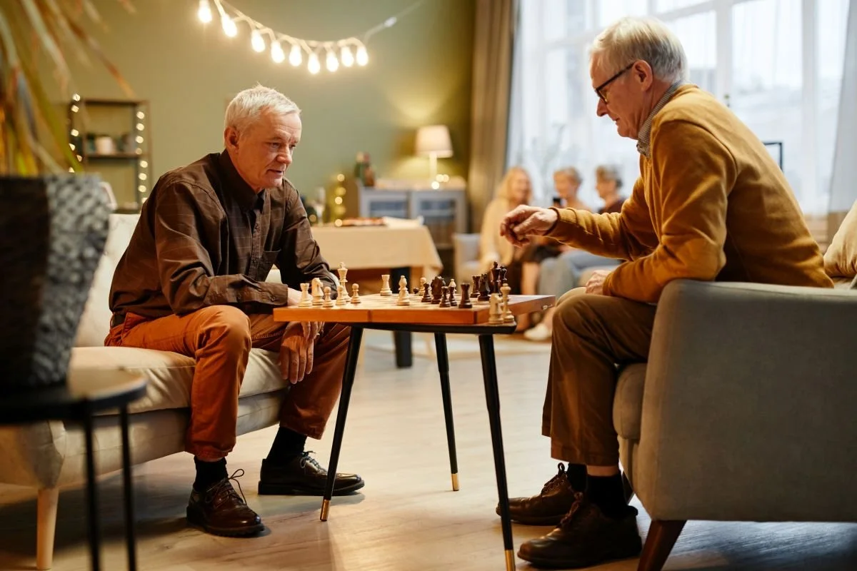 Senioren beim Schachspiel im Wohnzimmer – soziale Teilhabe und Logopädie bei Aphasie