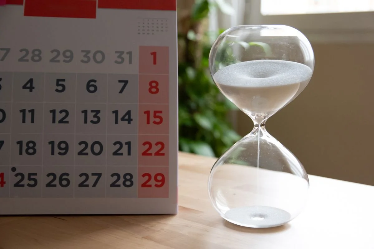 Sanduhr neben einem Kalender auf einem Tisch – wie bekomme ich einen Logopädietermin