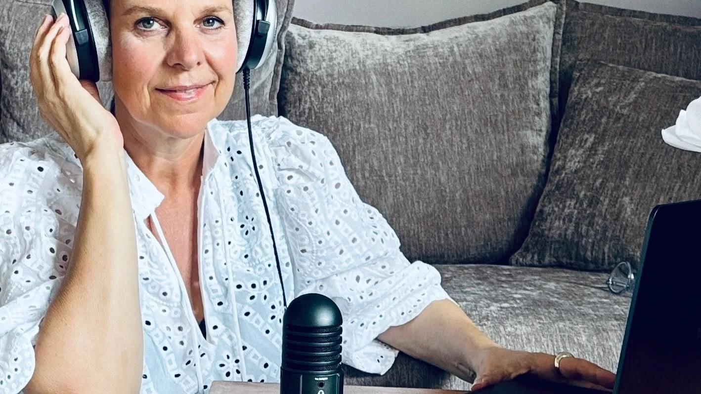 Podcast Coach Kathrin Pabst mit Headset sitzt auf einem Sofa, hat einen Laptop vor sich und spricht in ein Mikrofon.