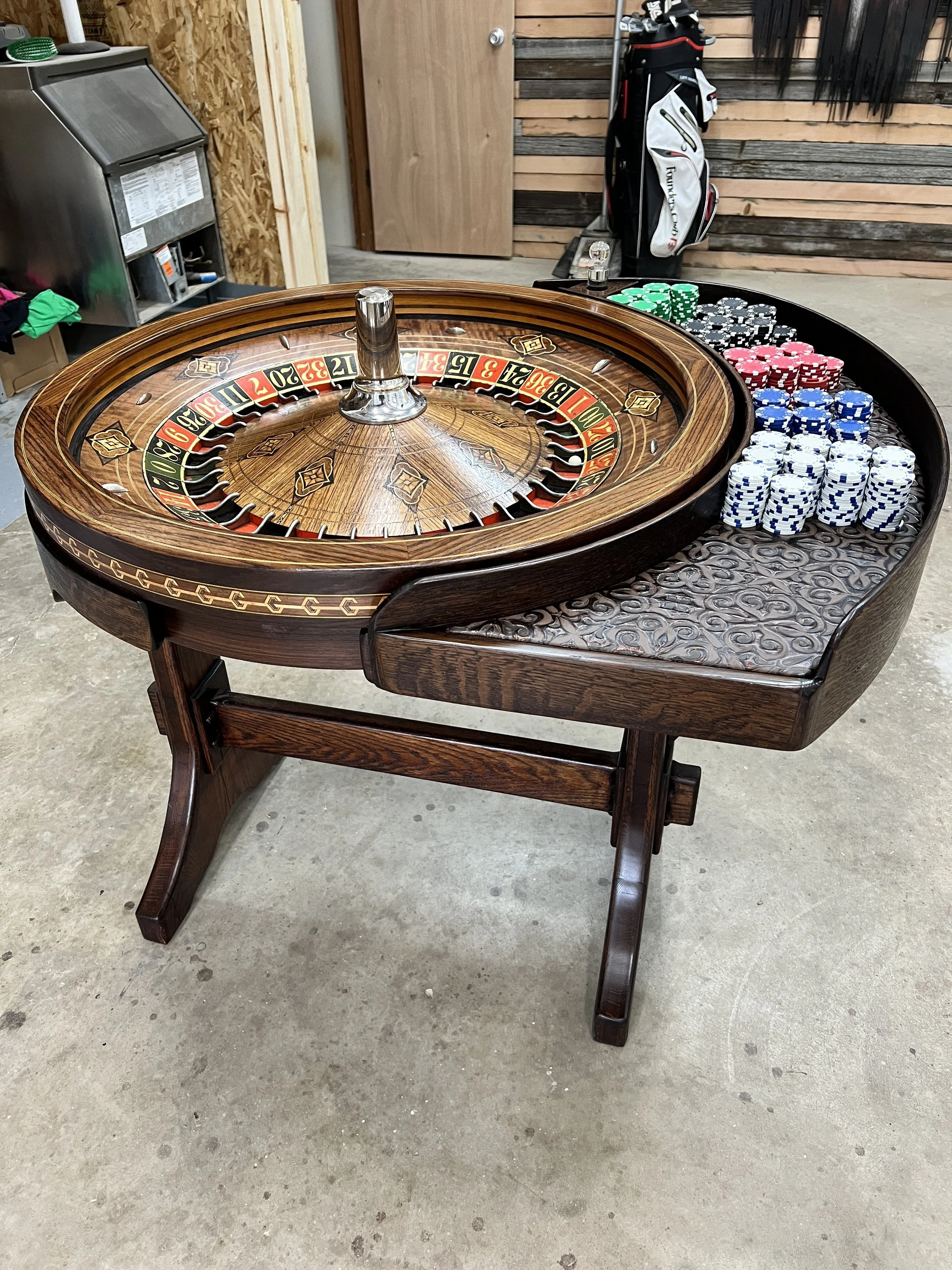 Wooden roulette table with a wheel and stacks of colored poker chips.