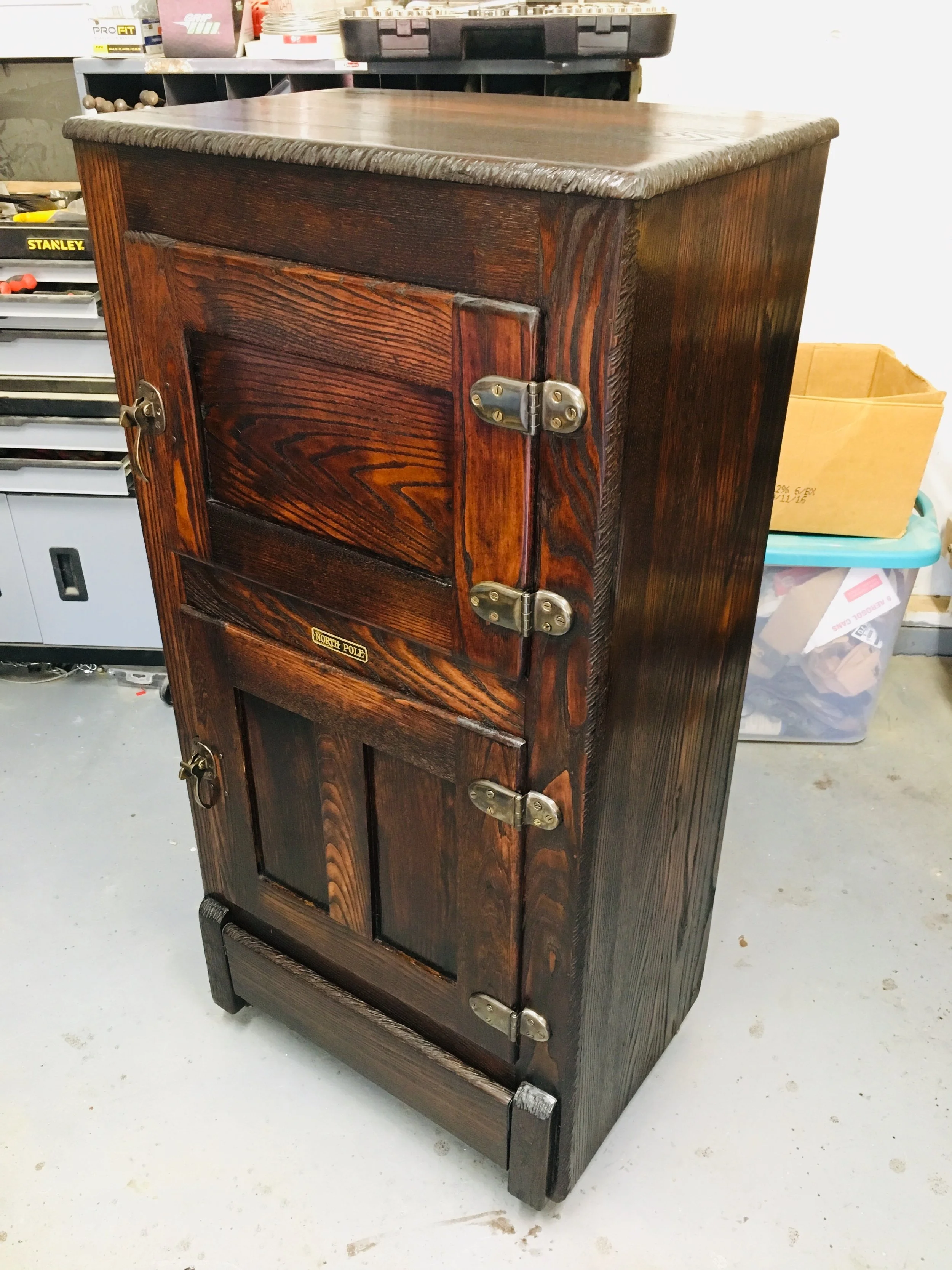 A vintage wooden icebox with brass hinges and latches.