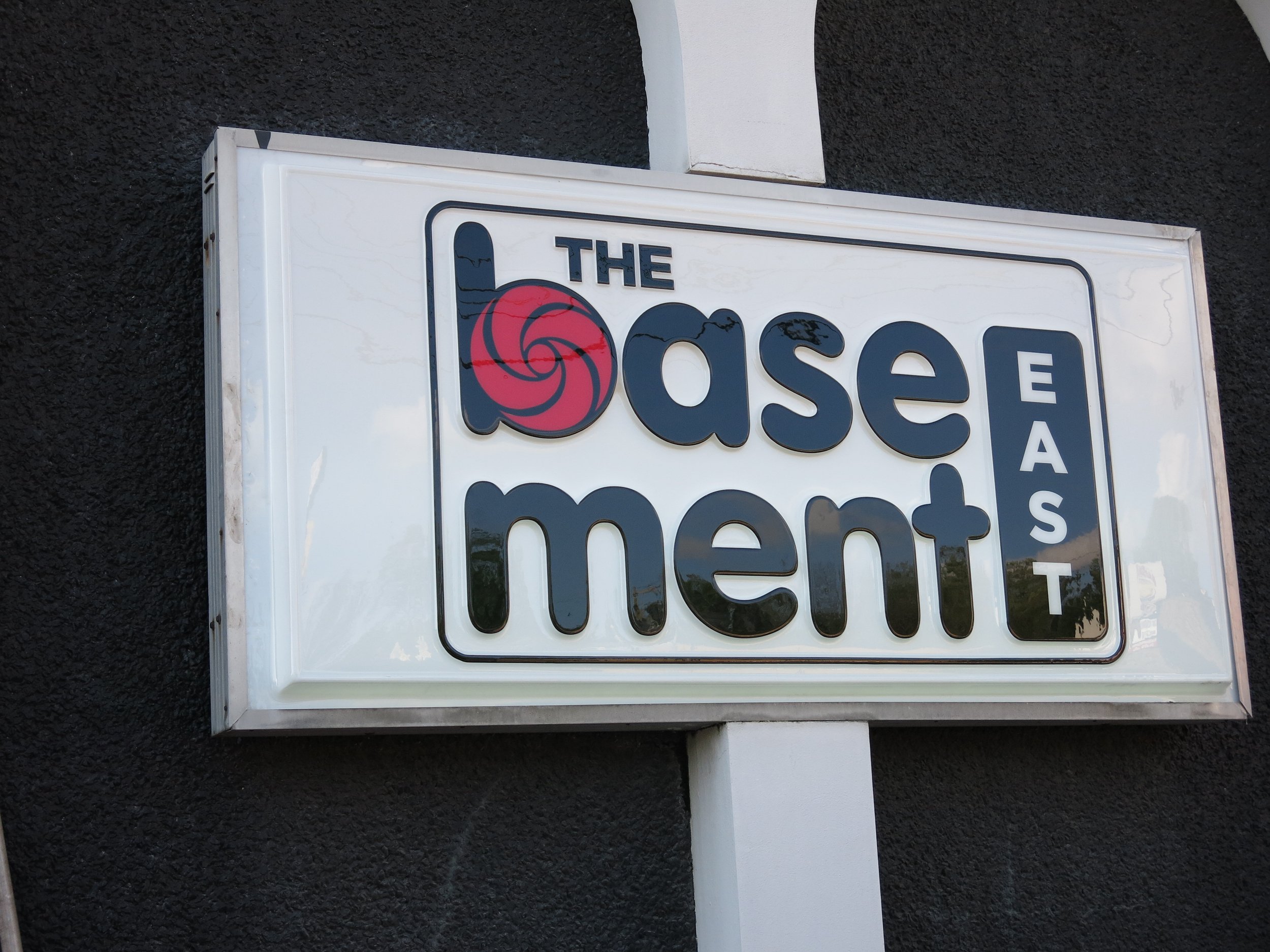 Sign for a venue called "The Basement East" with a stylized red spiral design on the letter 'b'.