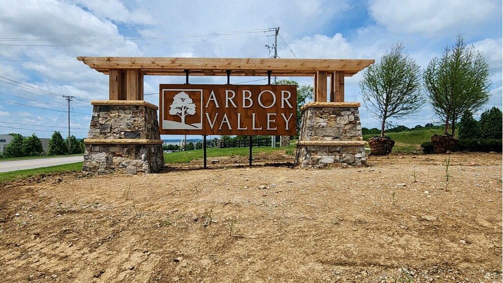 Entrance sign for Arbor Valley with stone pillars and wooden beams.