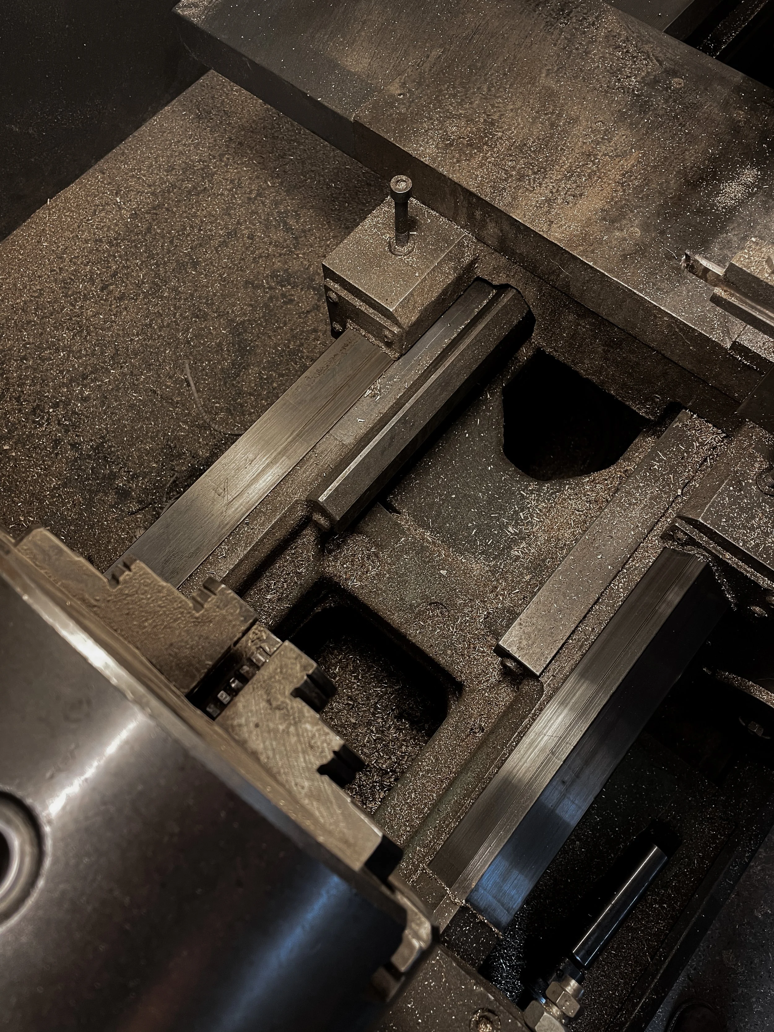 A close-up of a metal CNC machine with precision grooves and a worktable, showing metal shavings on its surface.