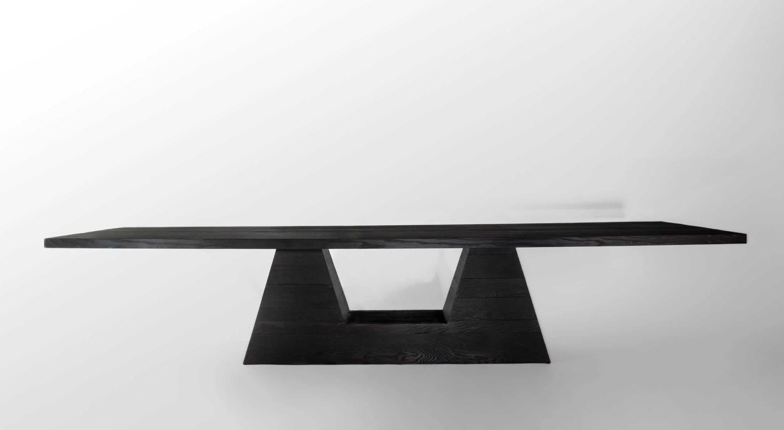 A modern black wooden table with a geometric base set against a plain white background.