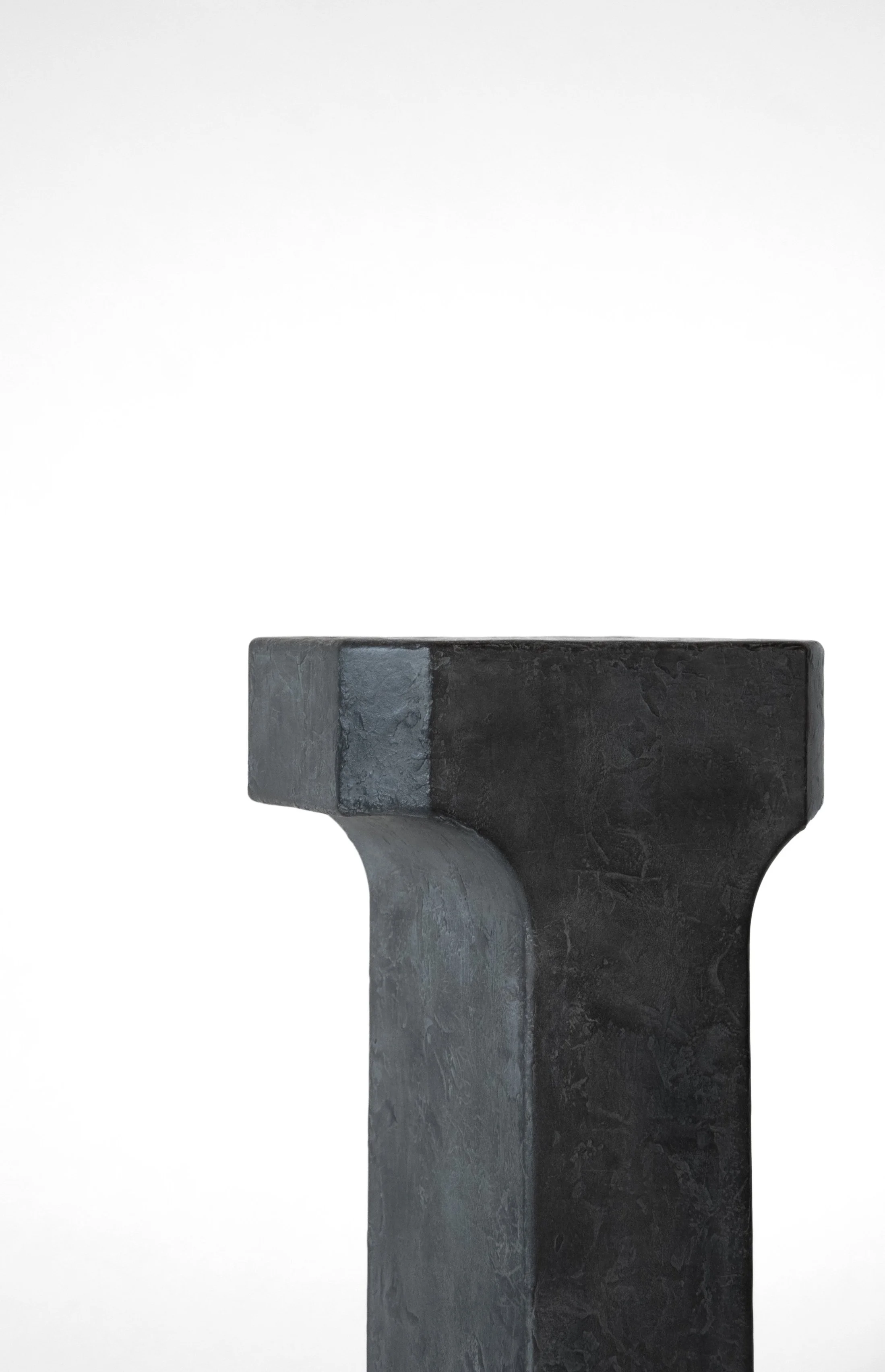Close-up of a black and gray textured stone pedestal or stand against a white background.