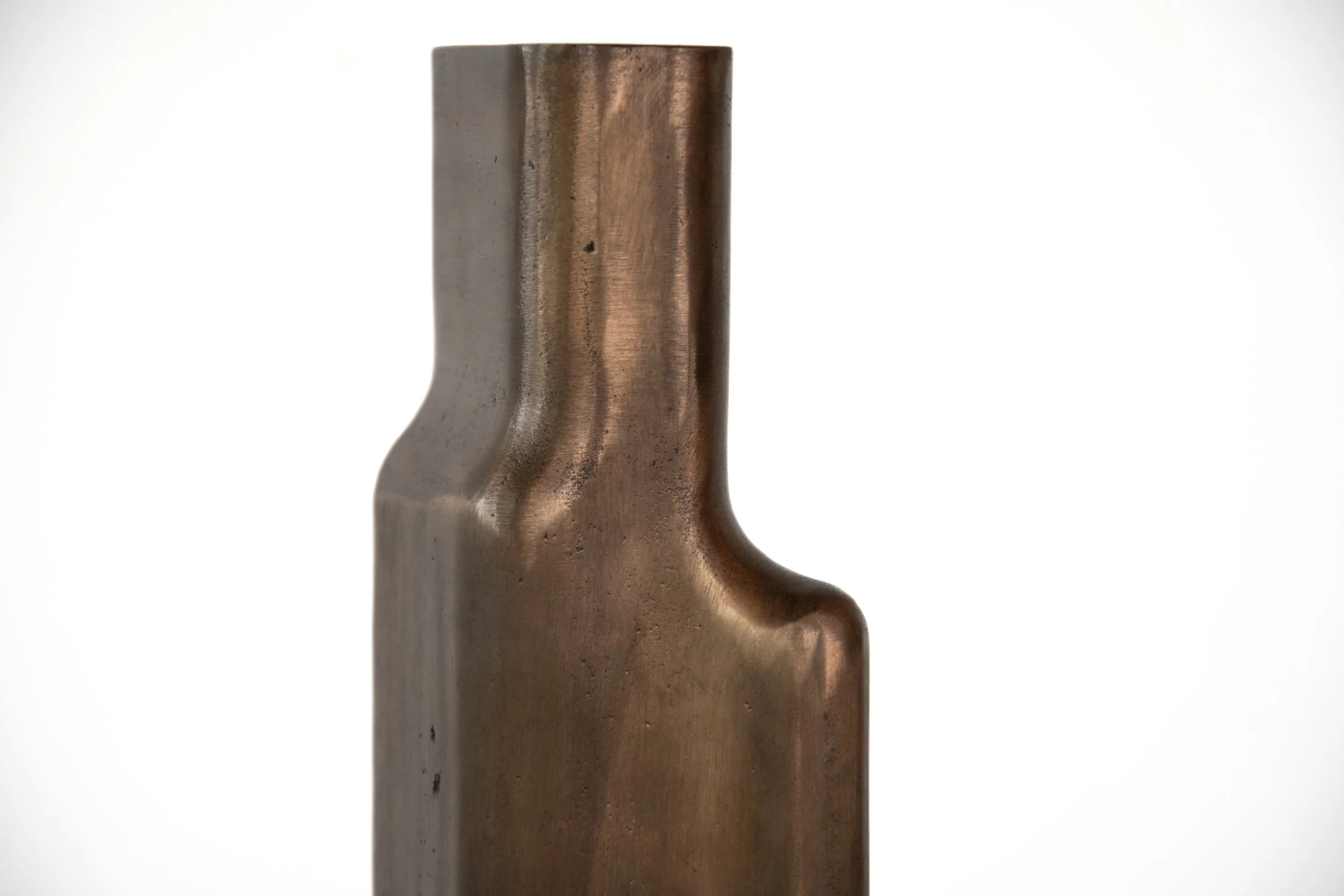 Close-up of a metallic object with a curved indentation, standing upright against a plain white background.