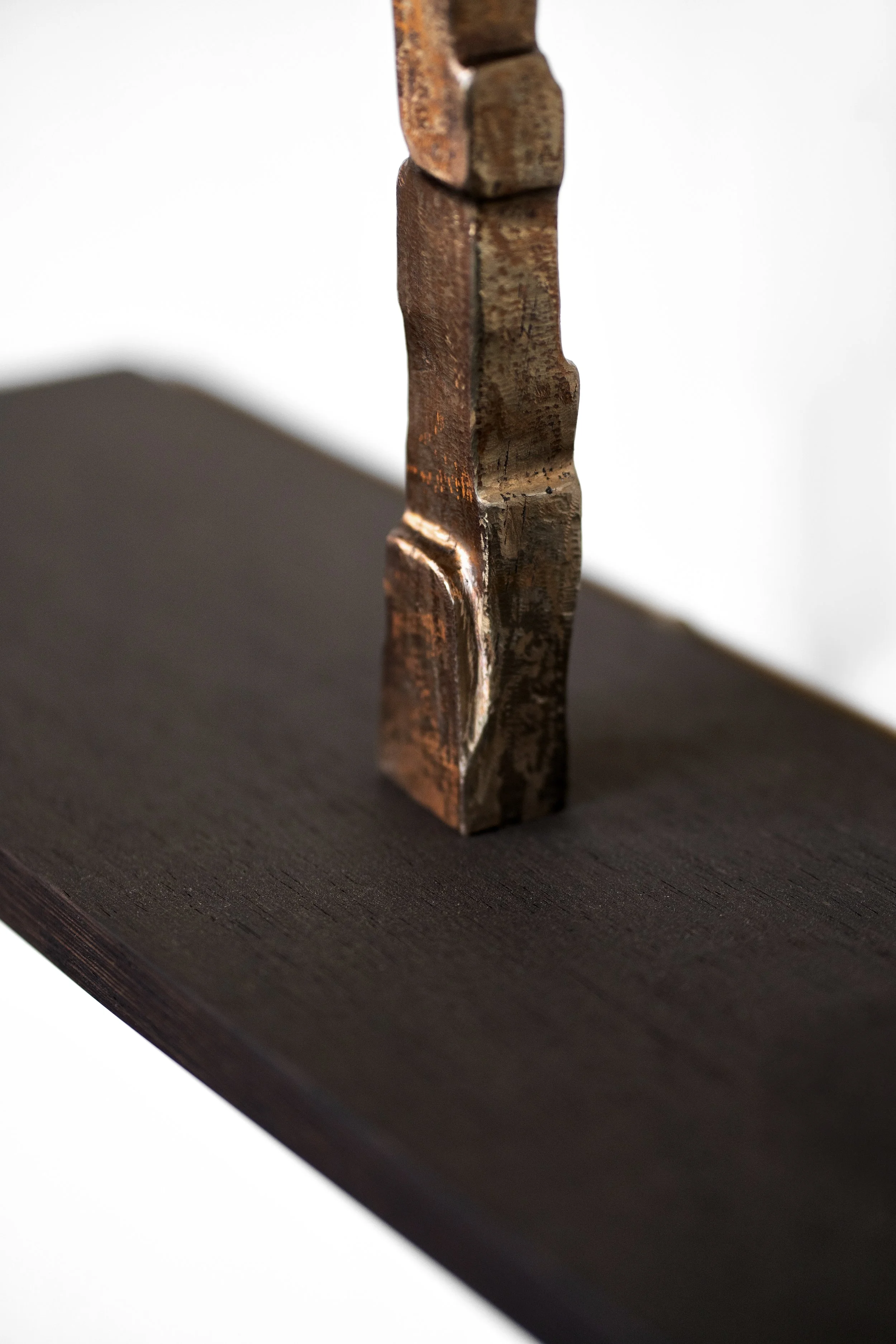 Close-up of a wooden chess piece standing on a dark wooden surface against a white background.
